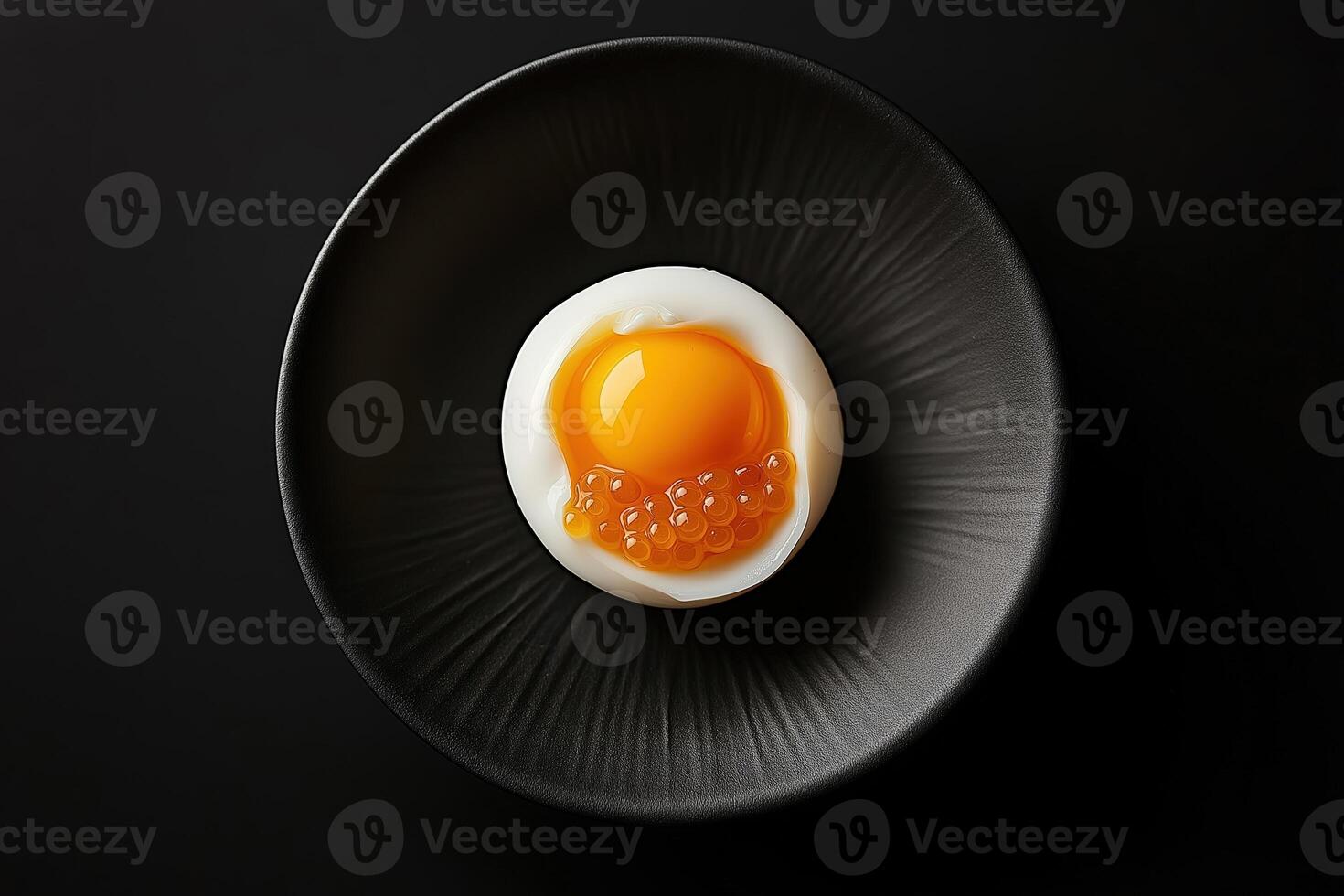 Soft boiled egg with salmon roe on black plate. Michelin star dish photo
