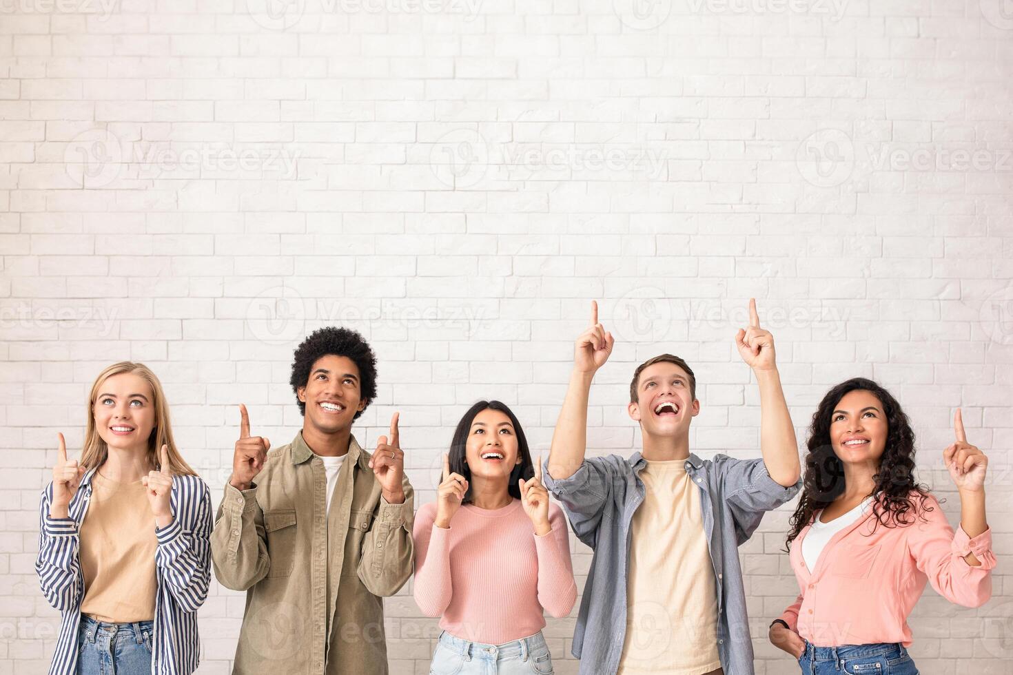 Amazing offer, great news and free space for text and ad. Surprised happy young international students show thumbs up and ready to study at university, on white wall background, studio shot, square photo