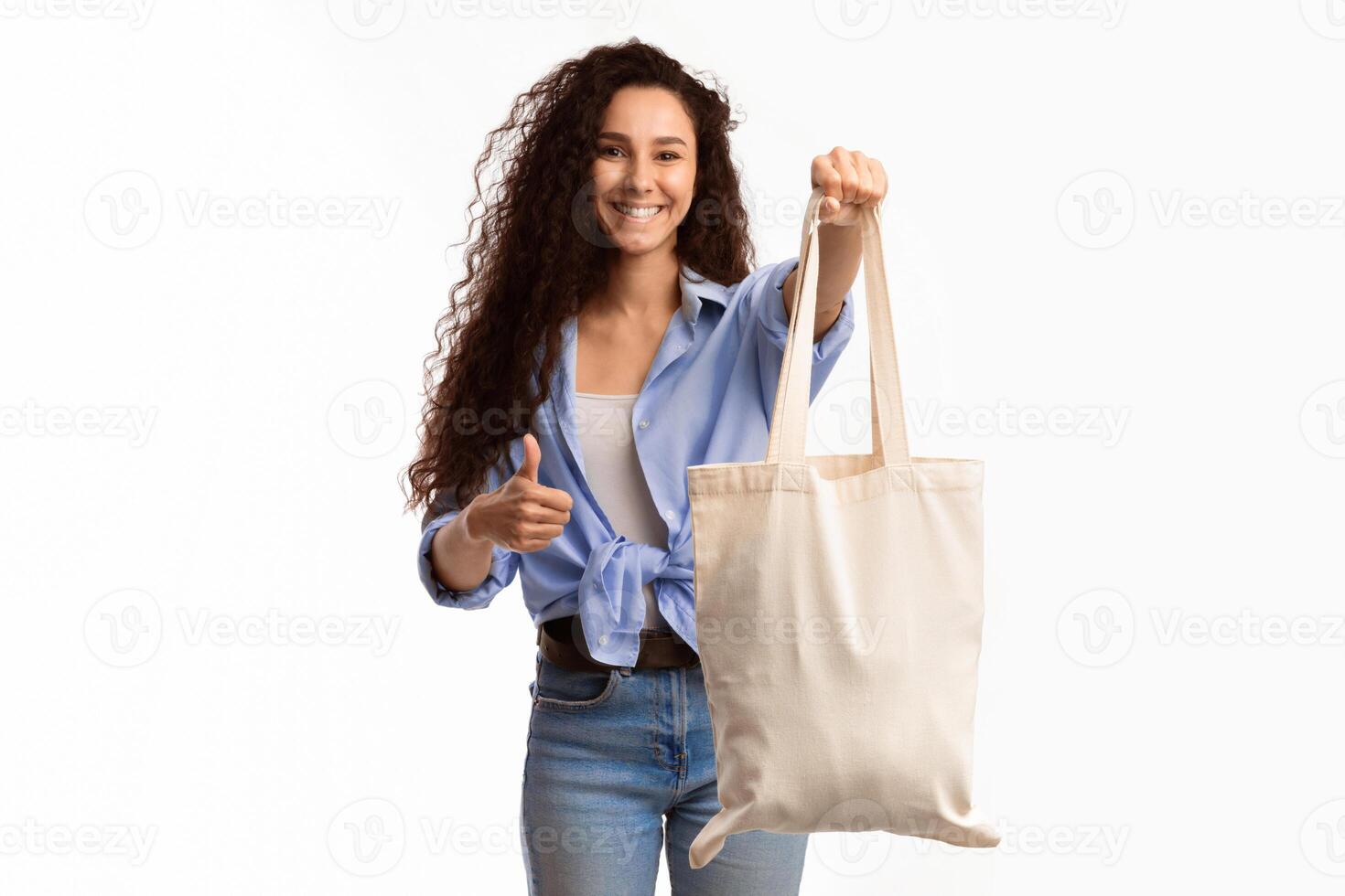 Cheerful Millennial Lady Showing White Cotton Shopper Bag Gesturing Thumbs Up In Approval Standing Over White Studio Background. Lady With Textile Handbag Approving Eco-Friendly Lifestyle With Like photo