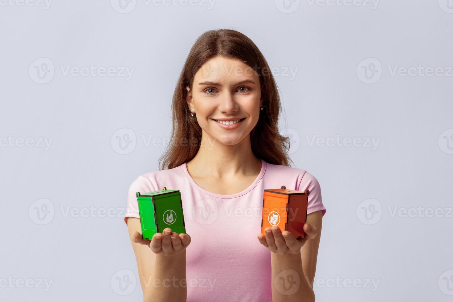 Waste Separation Concept. Portrait Of Happy Young Beautiful Woman Holding Little Wooden Toy Recycle Bins For Different Type Of Materials, Eco-Activist Lady Standing On Light Studio Background photo