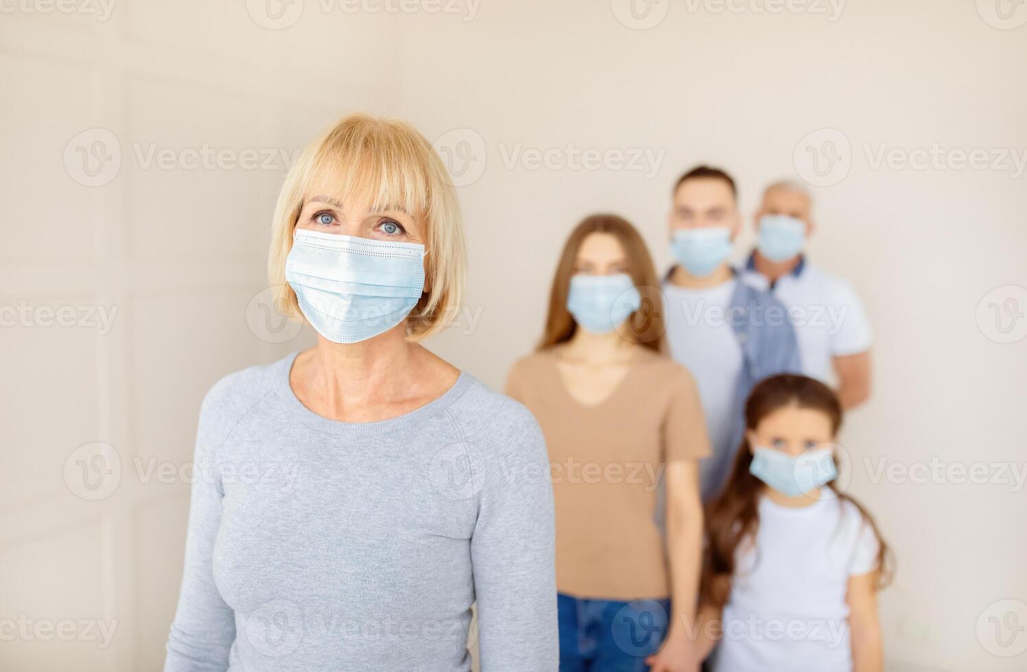 Senior woman in face mask waiting in line for vaccine against coronavirus at hospital, empty space. Mature female patient standing in queue for population covid-19 immunization photo