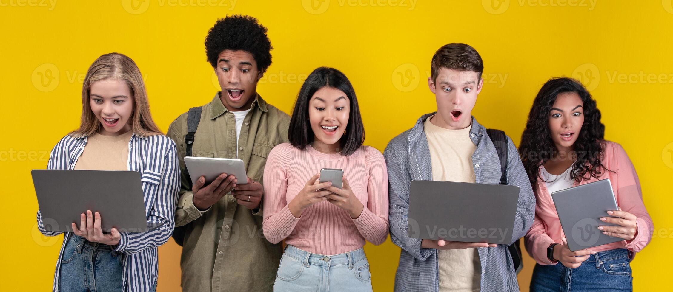 Facial emotions, amazing information, reaction to test results and social networks. Surprised zoomers multiracial people with open mouths look at gadgets, isolated on orange background, studio shot photo