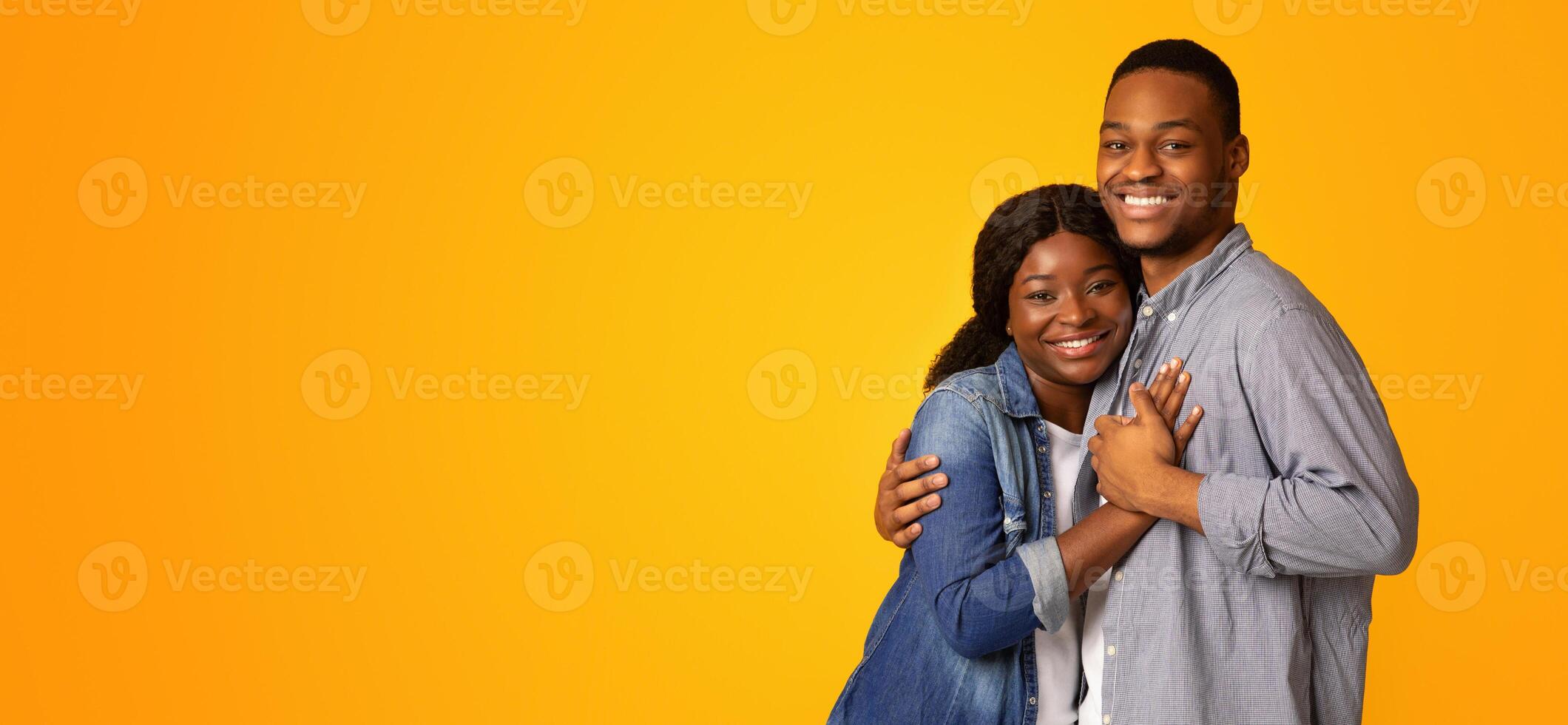 Portrait Of Affectionate Cheerful African American Couple Embracing While Posing Over Yellow Background, Happy Romantic Black Young Man And Woman Hugging And Smiling At Camera, Copy Space photo
