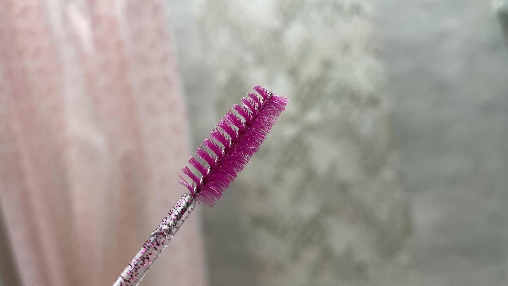 A pink brush with a pink handle is held up photo