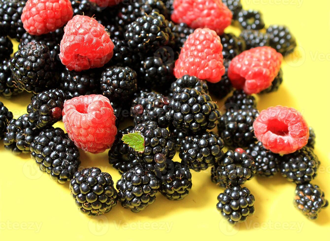Blackberry with raspberries on a yellow background. photo