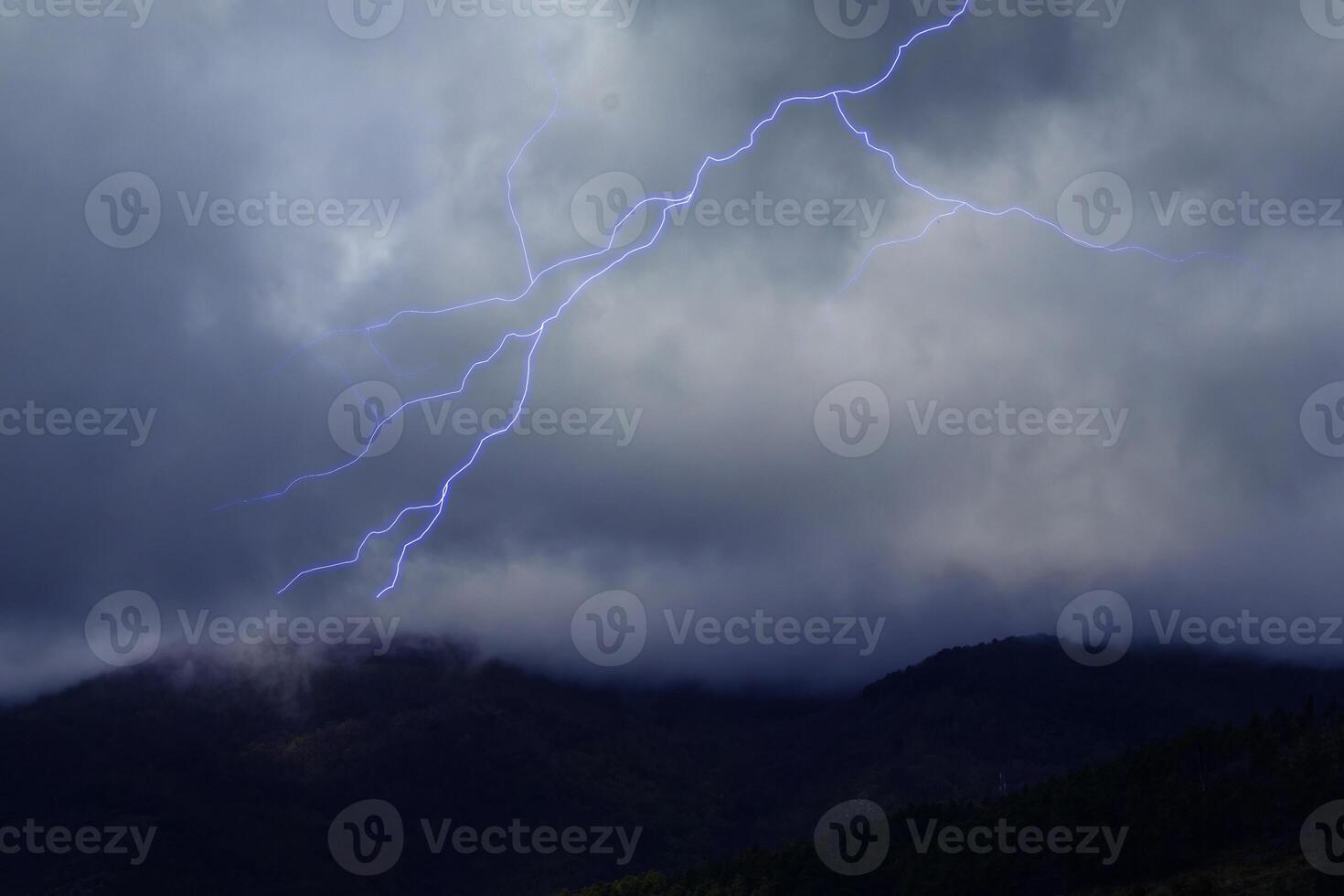 Lightning in the Dark Sky with Storm Clouds Over the Mountains photo