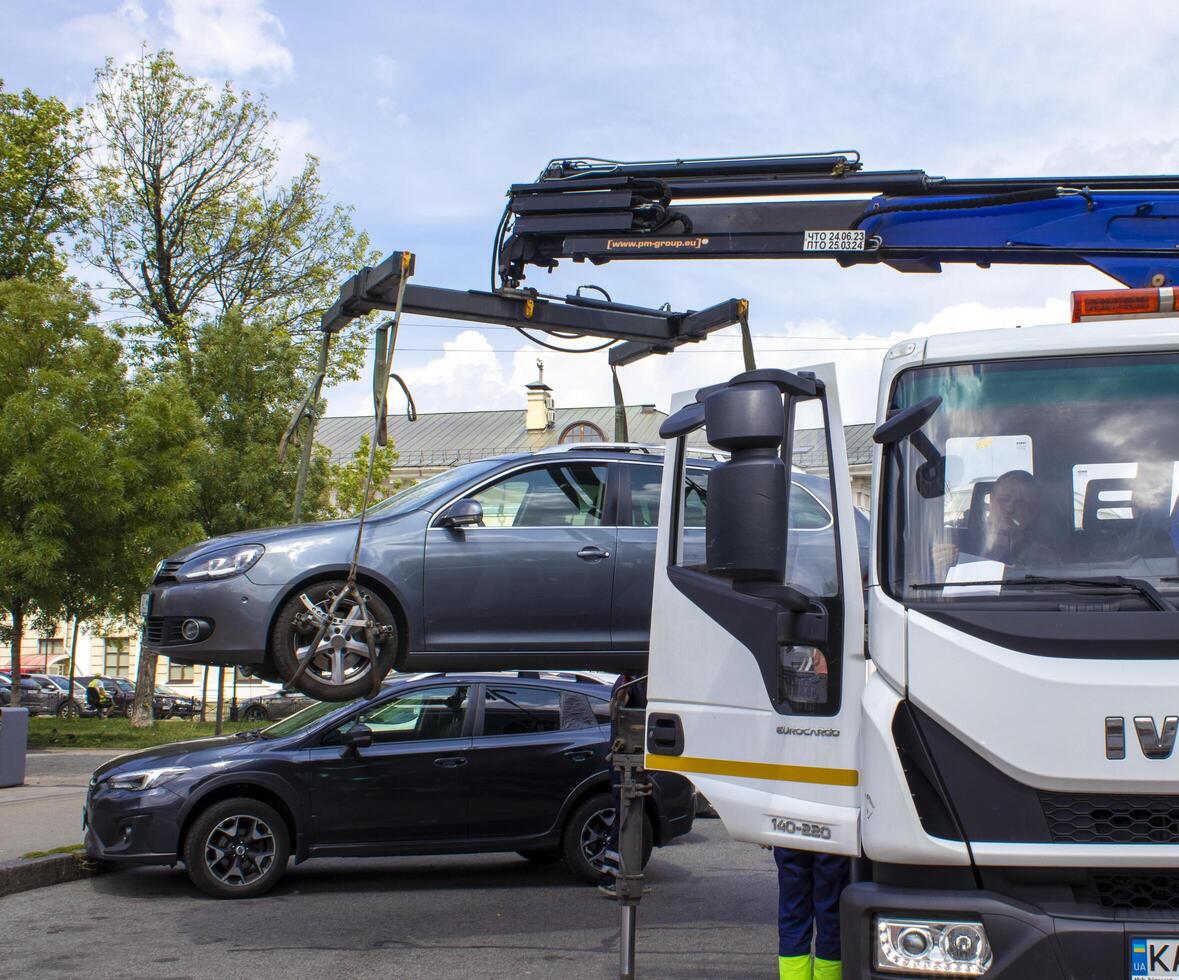 Kyiv, Ukraine, July 25, 2023, Car Evacuation in the Cty Center. The Car Was Lifted Onto a Tow Truck. The Car is Loaded Onto a Tractor in a Public Place for Transportation photo