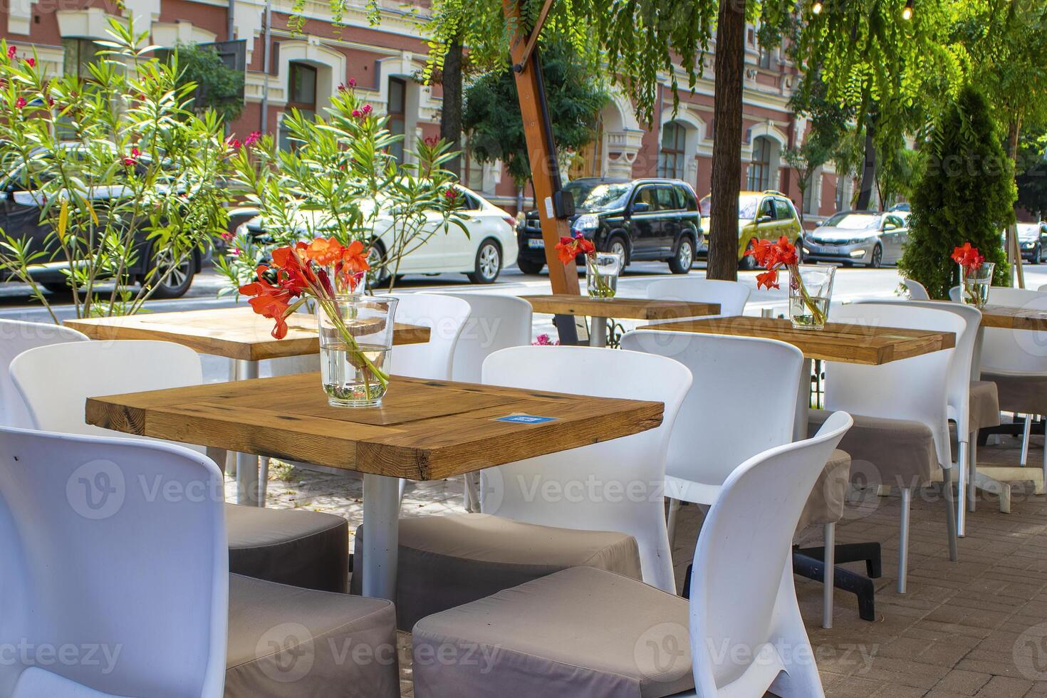 Beautiful Old Street in Kyiv With Deciduous Trees and Cafe Tables, Ukraine. Cute Design, Flowers on the Table, Flower Pots Along the Road photo
