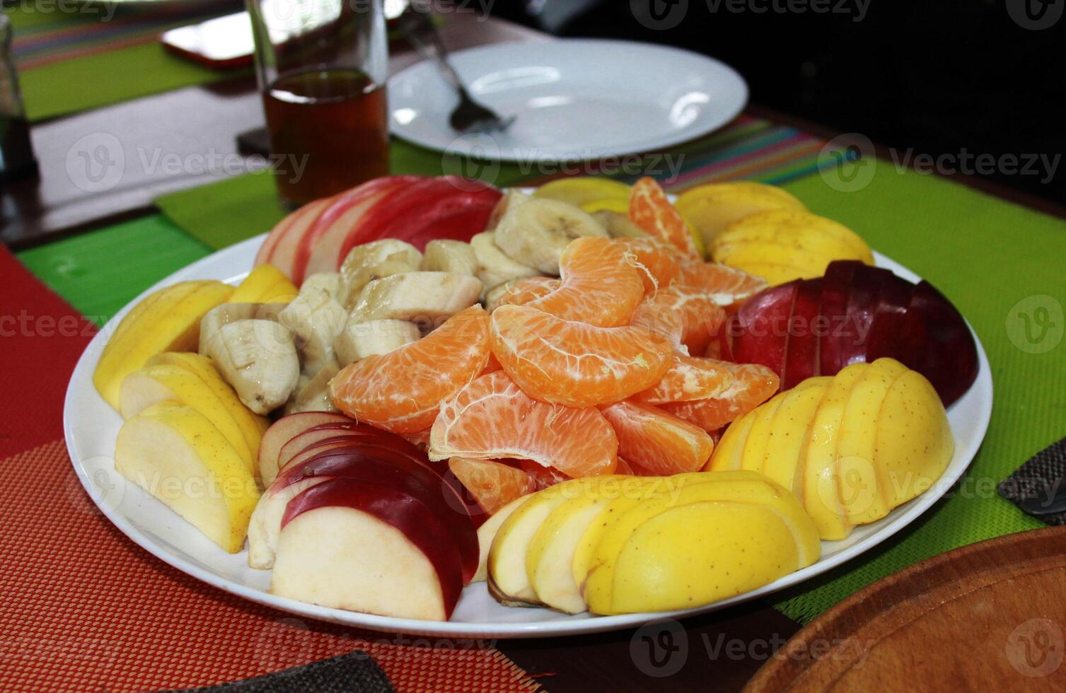 Plate with sliced fruit - banana, apple, orange. photo