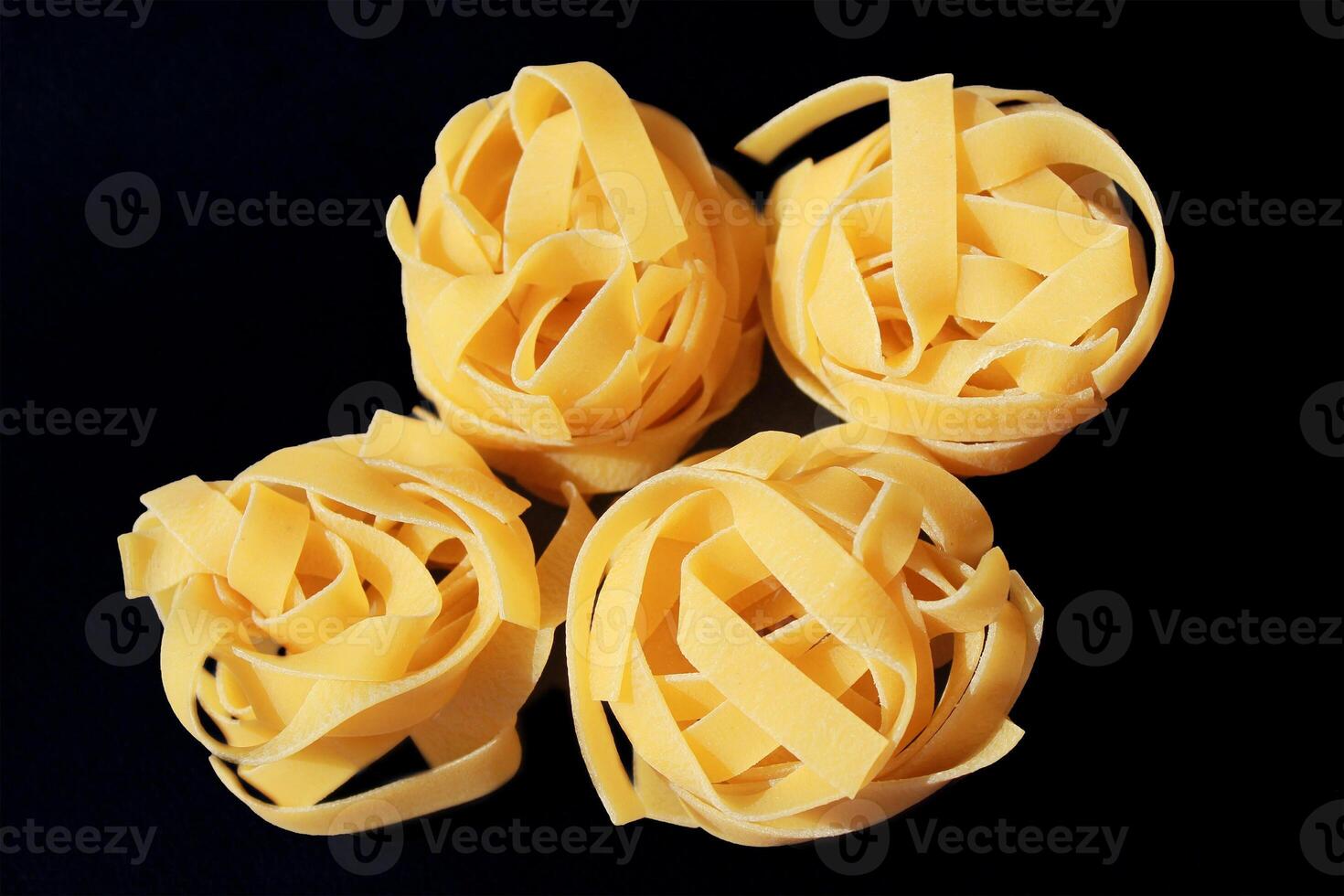 Italian rolled raw fettuccine pasta on the black background. photo
