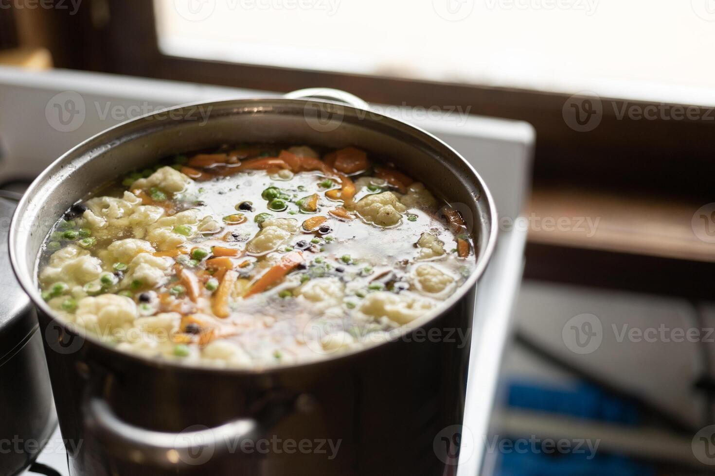 a pot of vegetable soup on the stove by the window photo