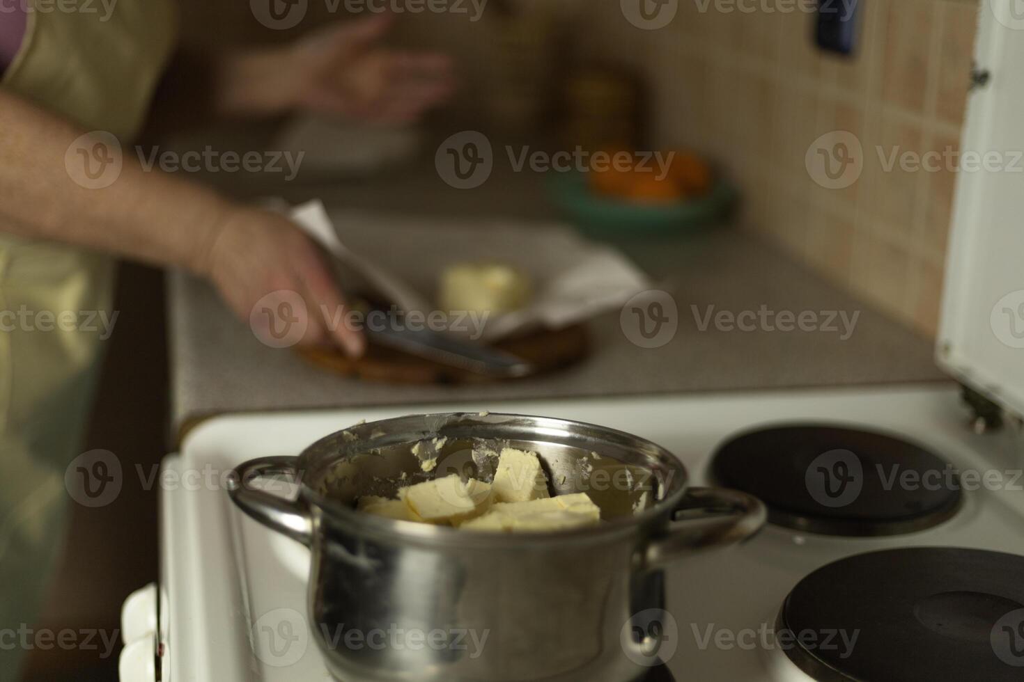 Senior woman's hands add sweet butter to a pan to melt, making ghee butter photo