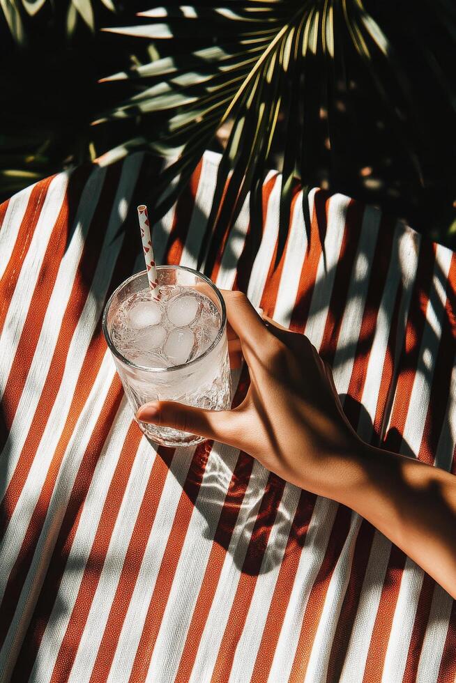 Refreshing Drink Held on Striped Fabric With Tropical Influences in Bright Sunlight photo