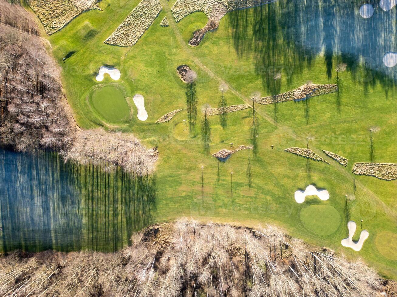 Stunning aerial perspective showcasing a well-maintained golf course with manicured greens, sand traps, and water hazards, nestled among trees during daytime. photo