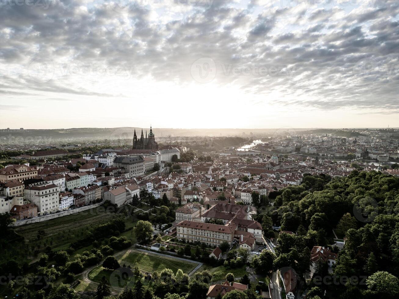 Soft morning light bathes Prague Castle and the surrounding cityscape in golden hues. Serenity fills the air as day breaks over this historic landmark, inviting exploration. photo