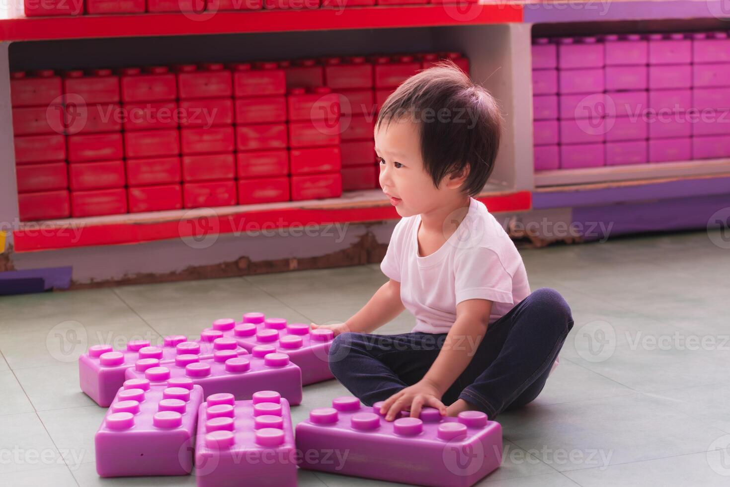 Little Asian boy happily playing with toy blocks at his home, muscle development, learning and creativity from playing. 2 year old boy. photo