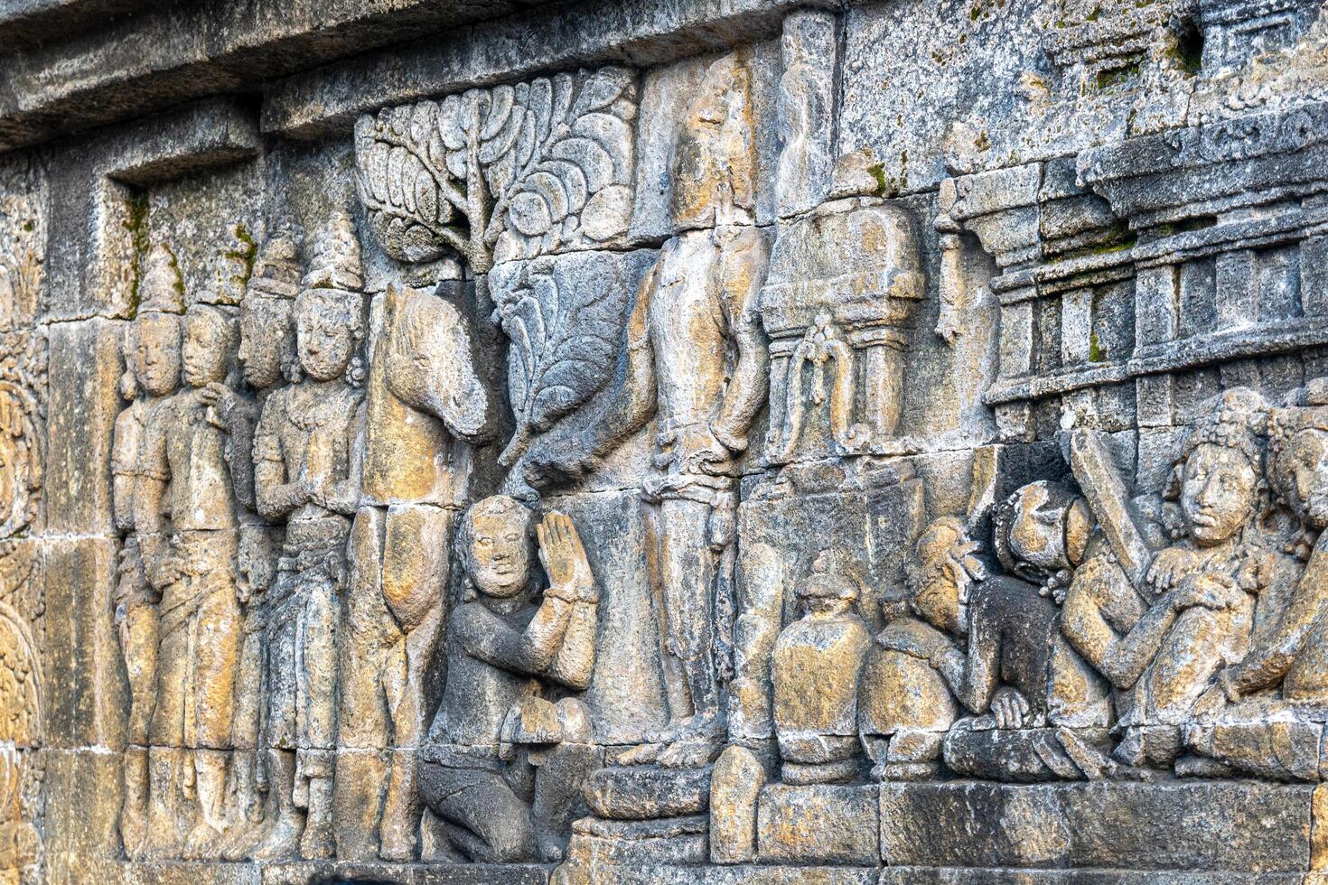 Ancient stone relief depicts figures, a horse, and worship scenes in detailed temple carvings. photo