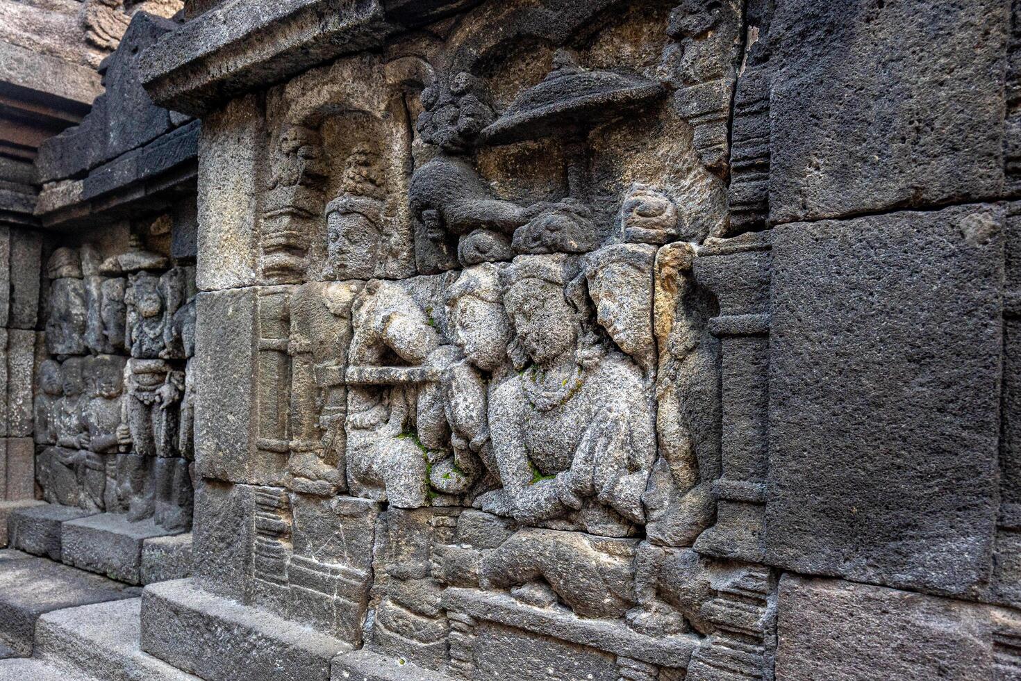 Ancient stone carvings showing detailed human and symbolic figures on a temple wall. photo