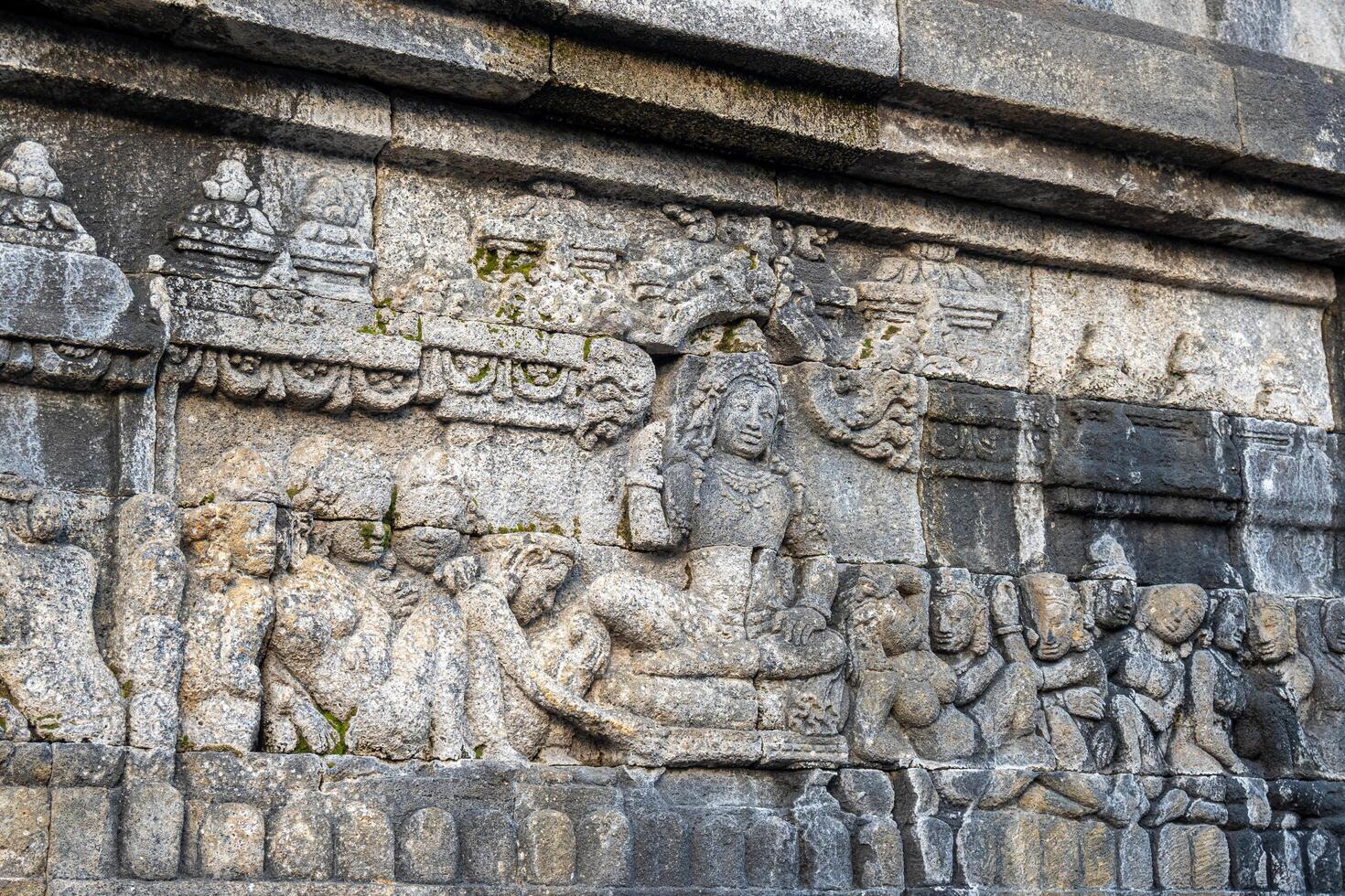 A stone relief shows a seated figure surrounded by followers in detailed ancient temple carvings. photo