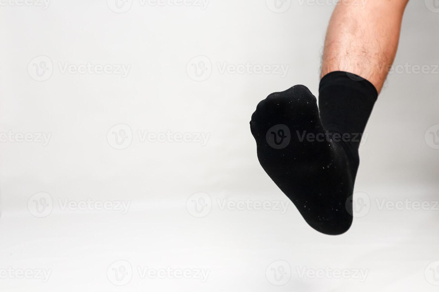 Studio shot of a male foot wearing a black sock against a plain white backdrop with space for text photo