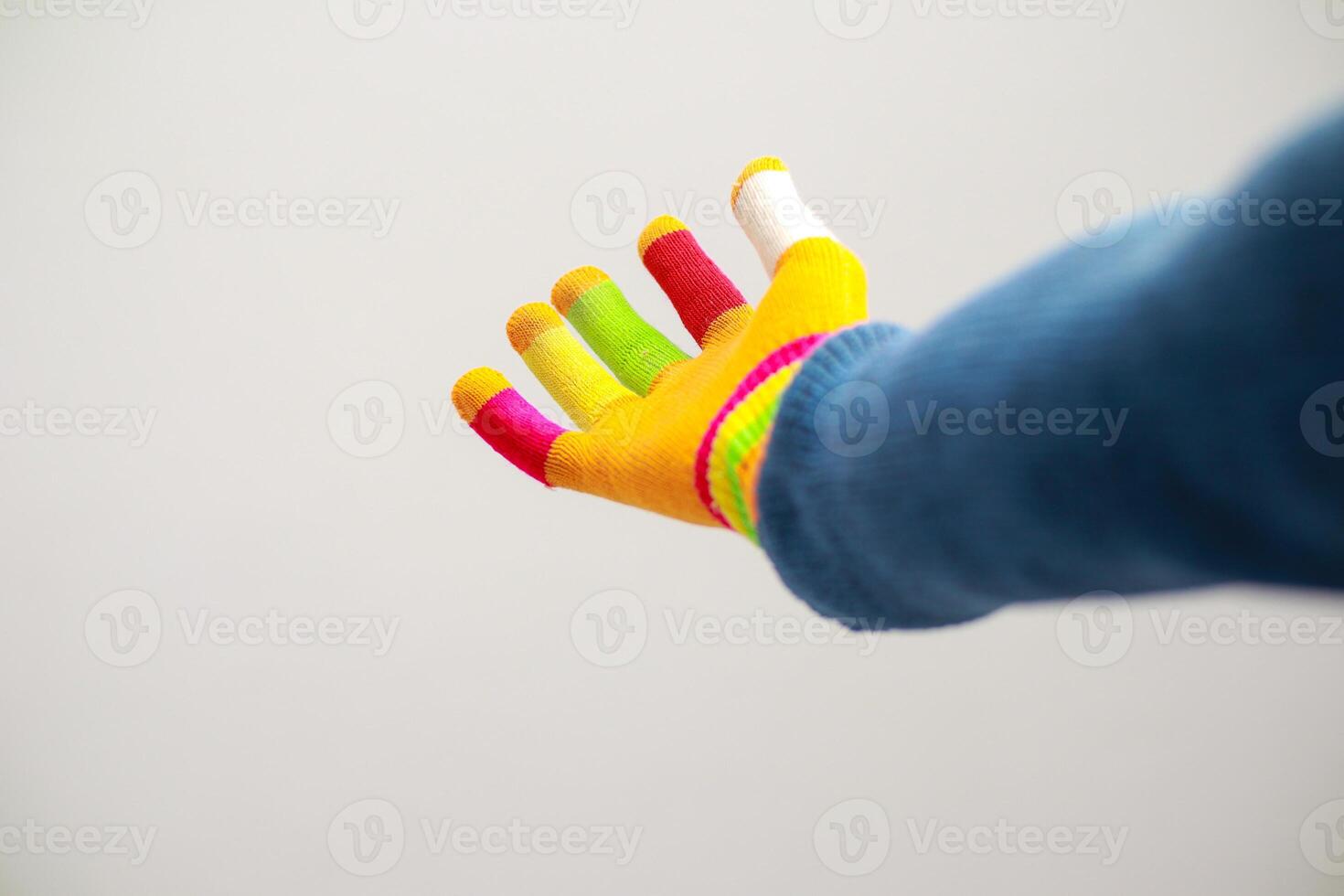A vibrant hand, covered in a colorful glove with rainbow accents and painted fingertips against a stark white backdrop photo