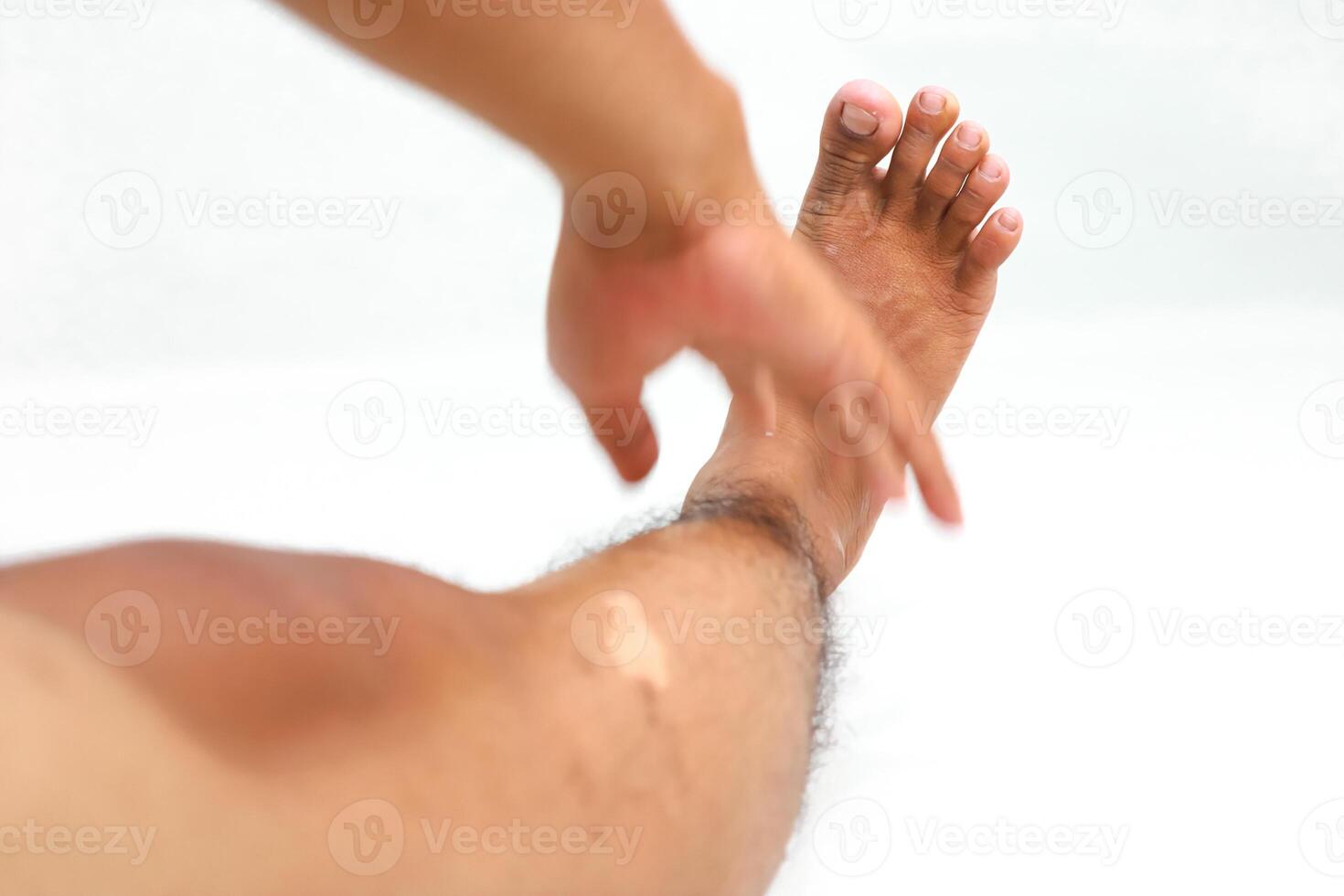 Close-up of a person applying lotion to their foot and leg for skin care and health routine photo