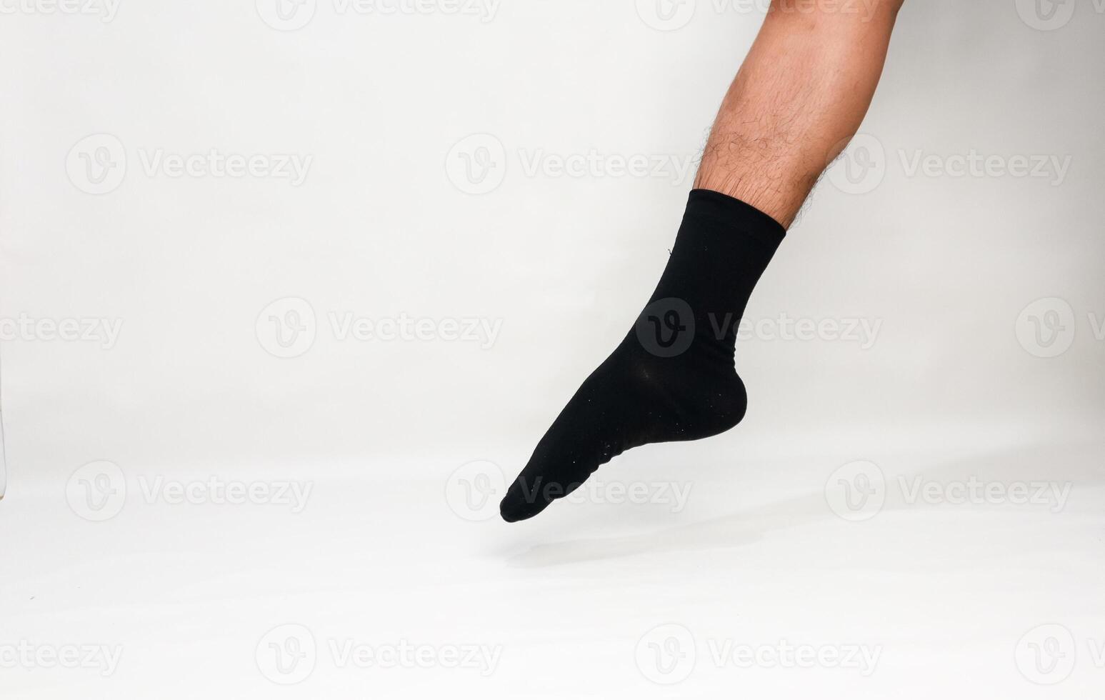 Isolated image of a man's leg and foot wearing a black sock, studio shot against white backdrop for fashion apparel photography photo