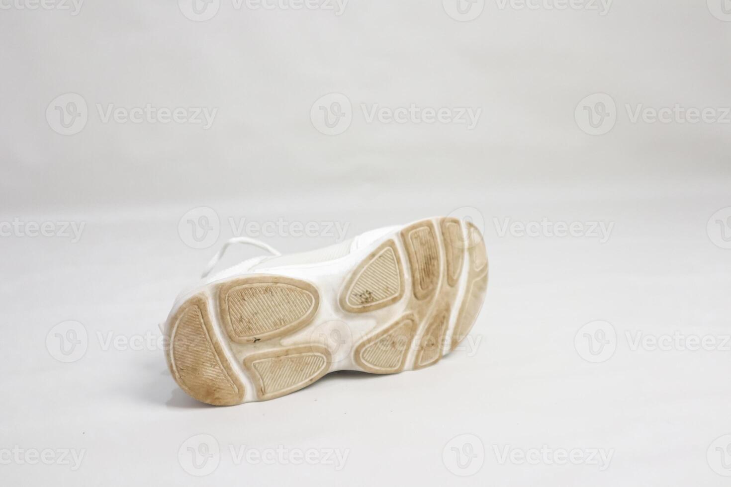 Close-up of a single white sneaker with a dirty sole against a white background photo