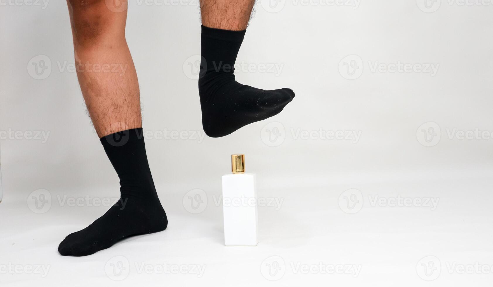 Quirky studio shot of a man's legs and a perfume bottle in a playful, humorous concept photo