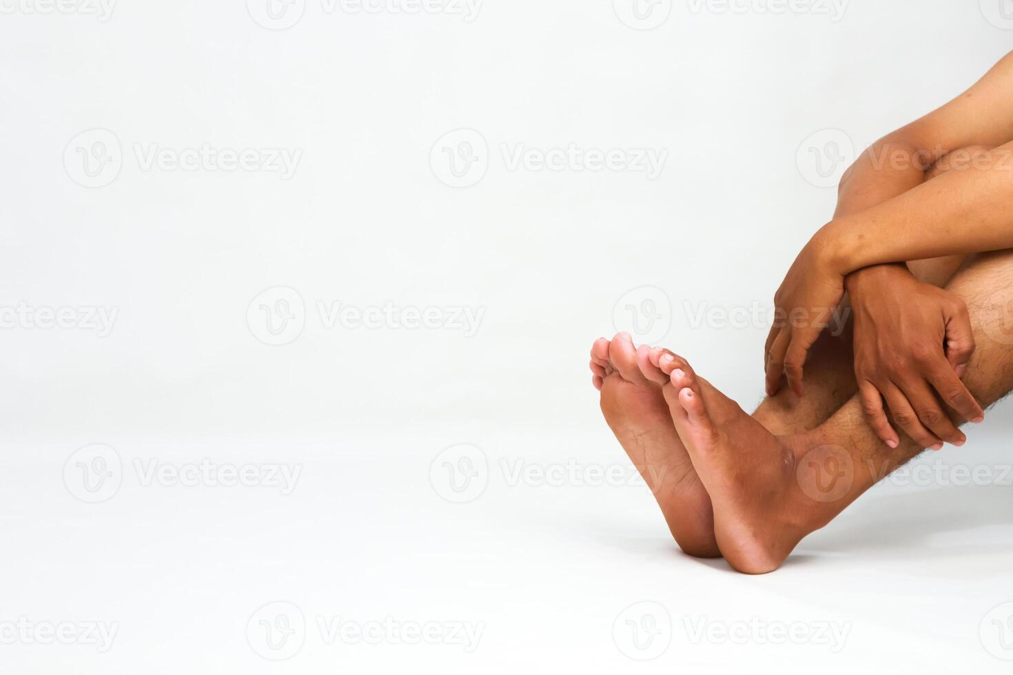 Man Sitting with Arms Around Legs on White Background Showcasing Body and Relaxation photo