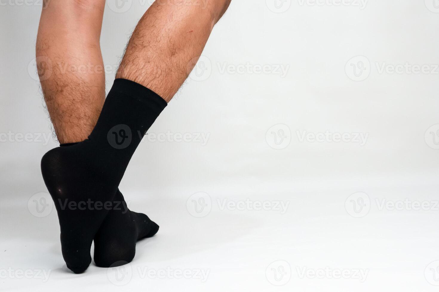 A man with hairy legs standing with his legs crossed wearing black socks on a white background photo