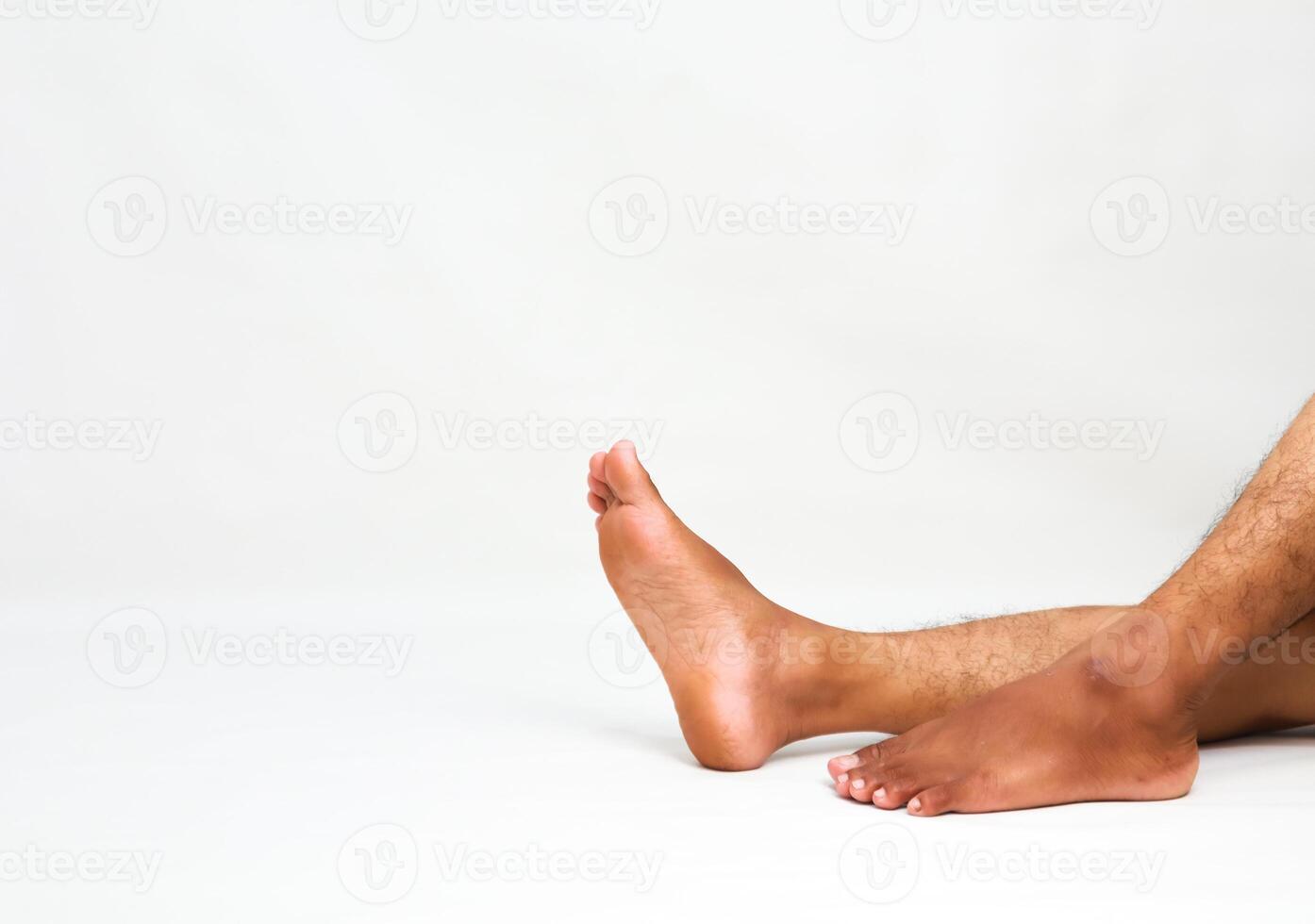 Relaxed dark-skinned man's legs and feet on a white surface, showcasing rest and relaxation for wellness promotions photo