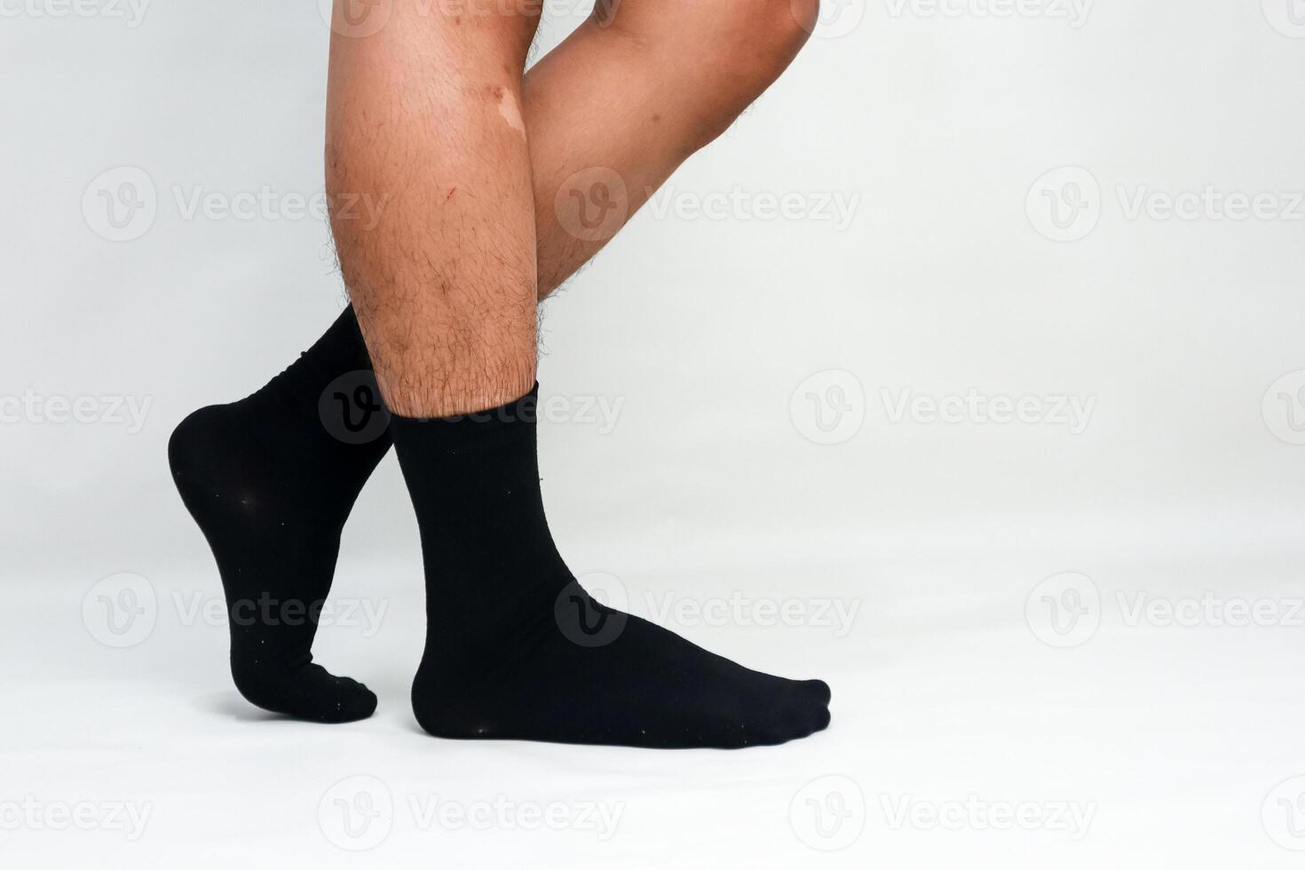 Close-up of a Person's Legs and Feet Wearing Black Socks Against a White Background photo
