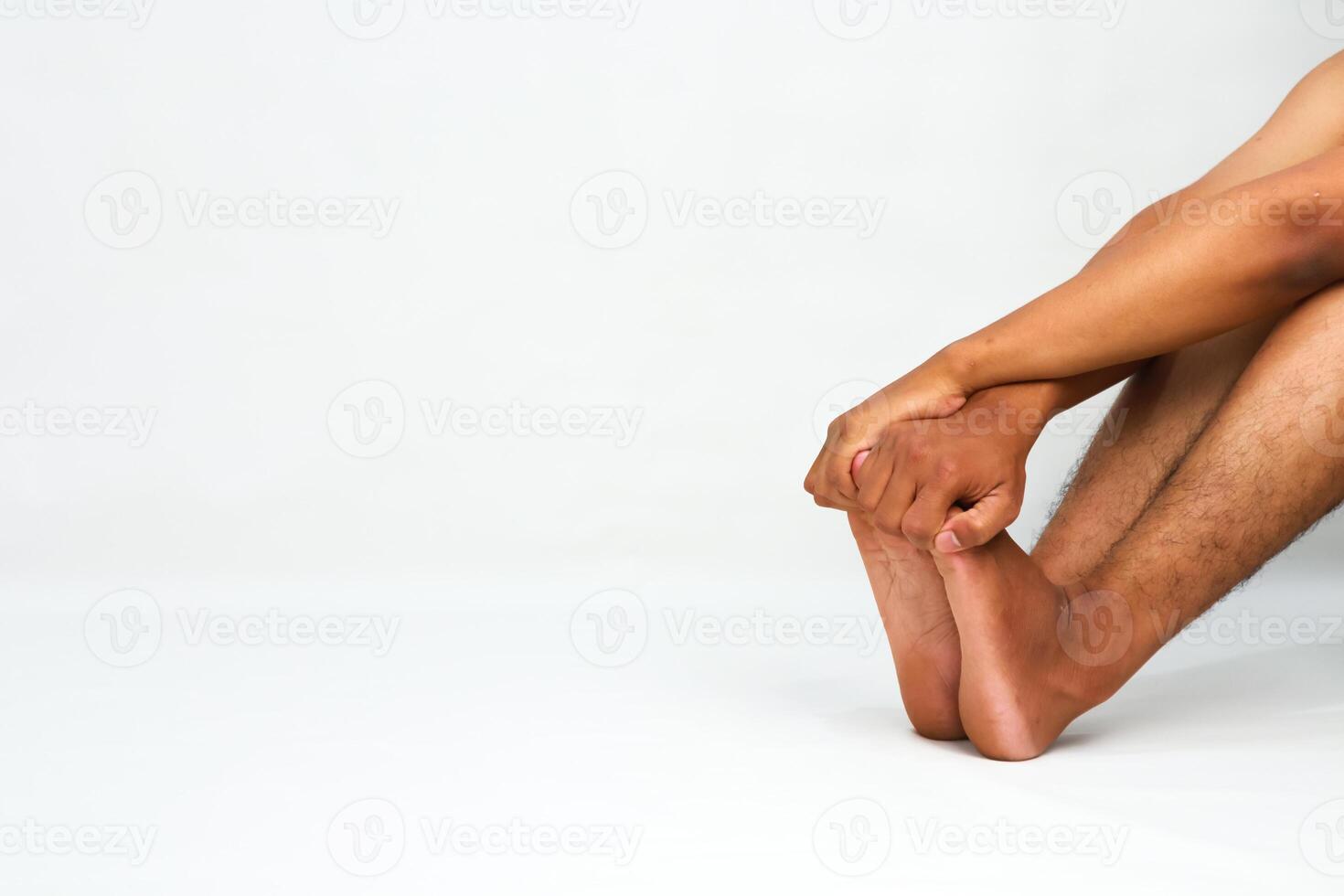 Close-up of a person's legs and arms on a white background, focusing on hand-foot connection and relaxation photo