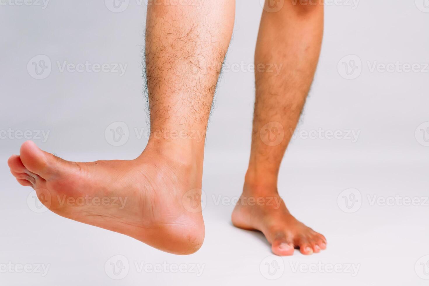 Close-up of a man's legs and feet against a plain background, showcasing foot flexibility photo
