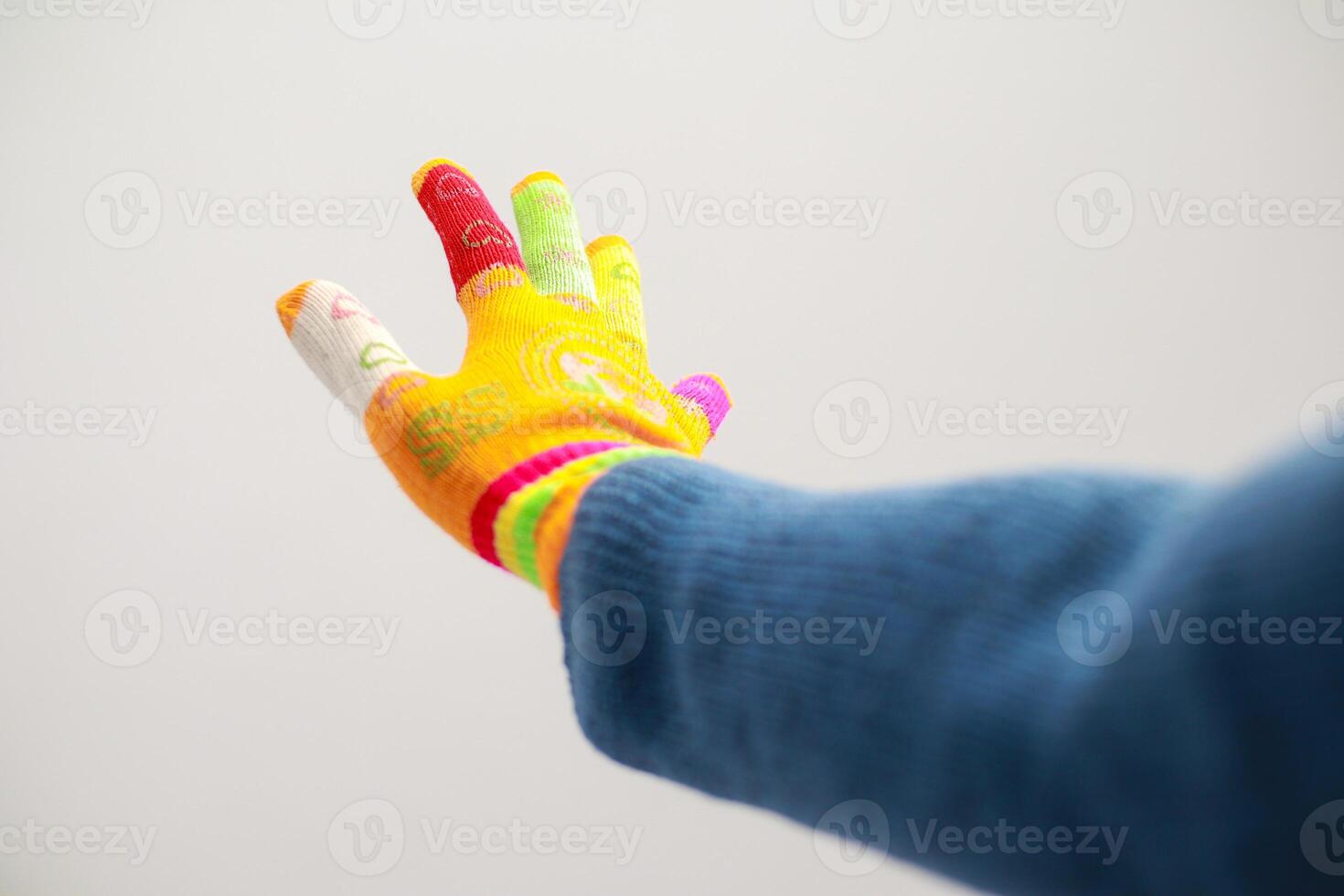 Colorful knitted glove on a hand reaching out, set against a stark white background for creative expression photo