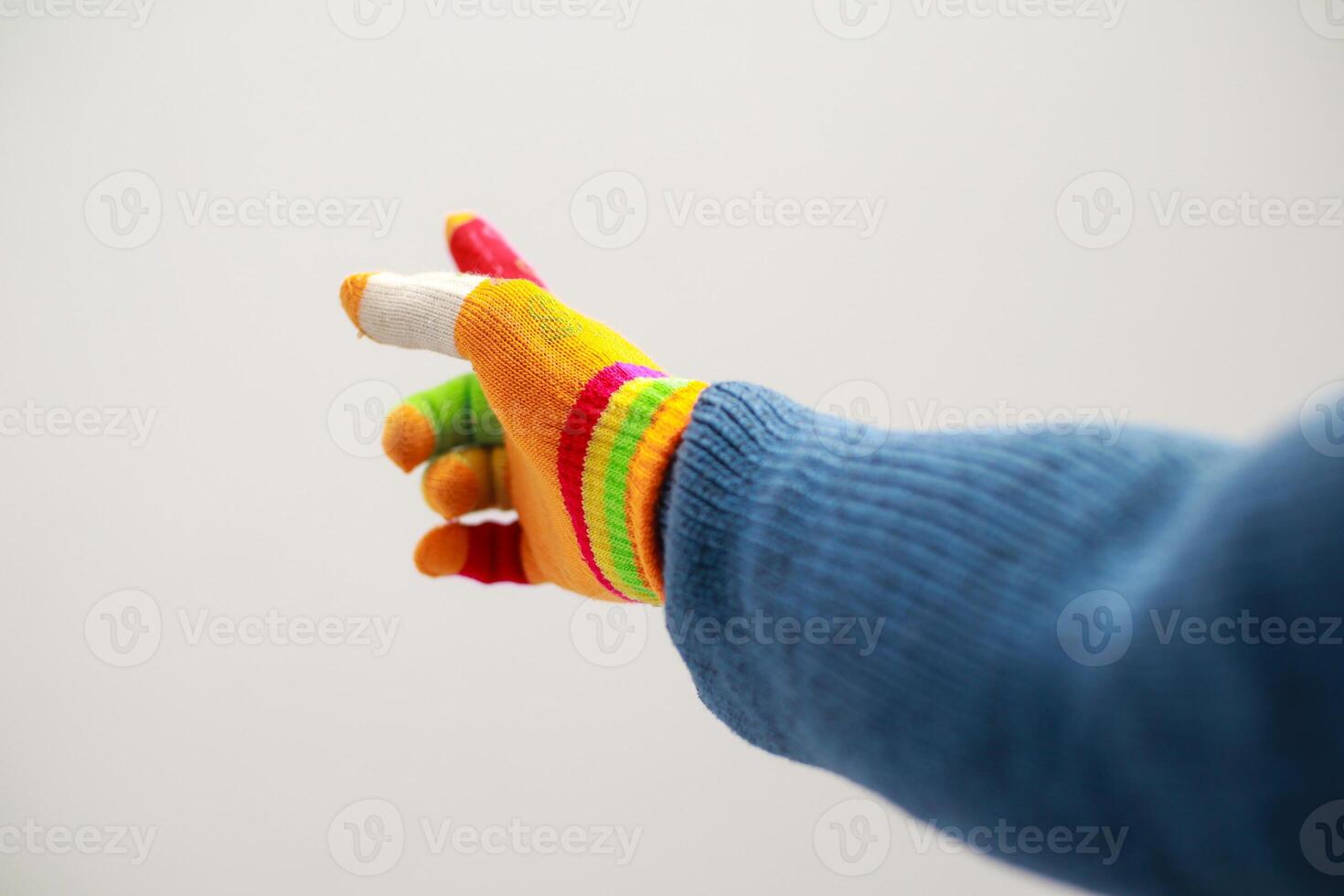 A playful hand wearing a vibrant, rainbow-striped glove points towards an imaginative world photo