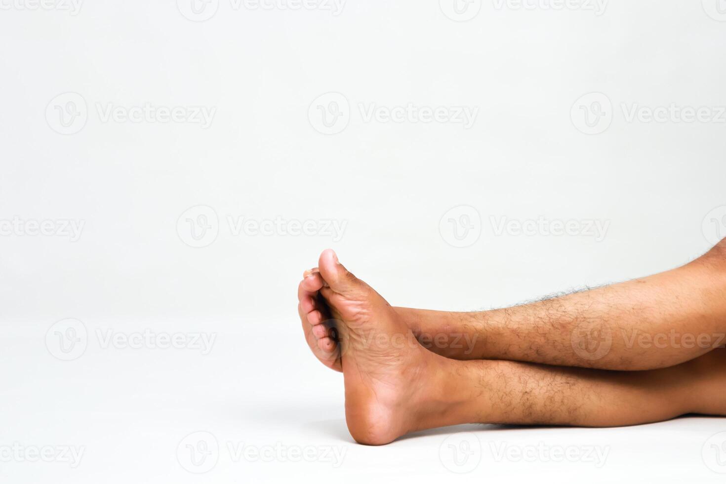 Relaxed posture showcasing human feet and legs against a clean white backdrop highlighting natural tones photo