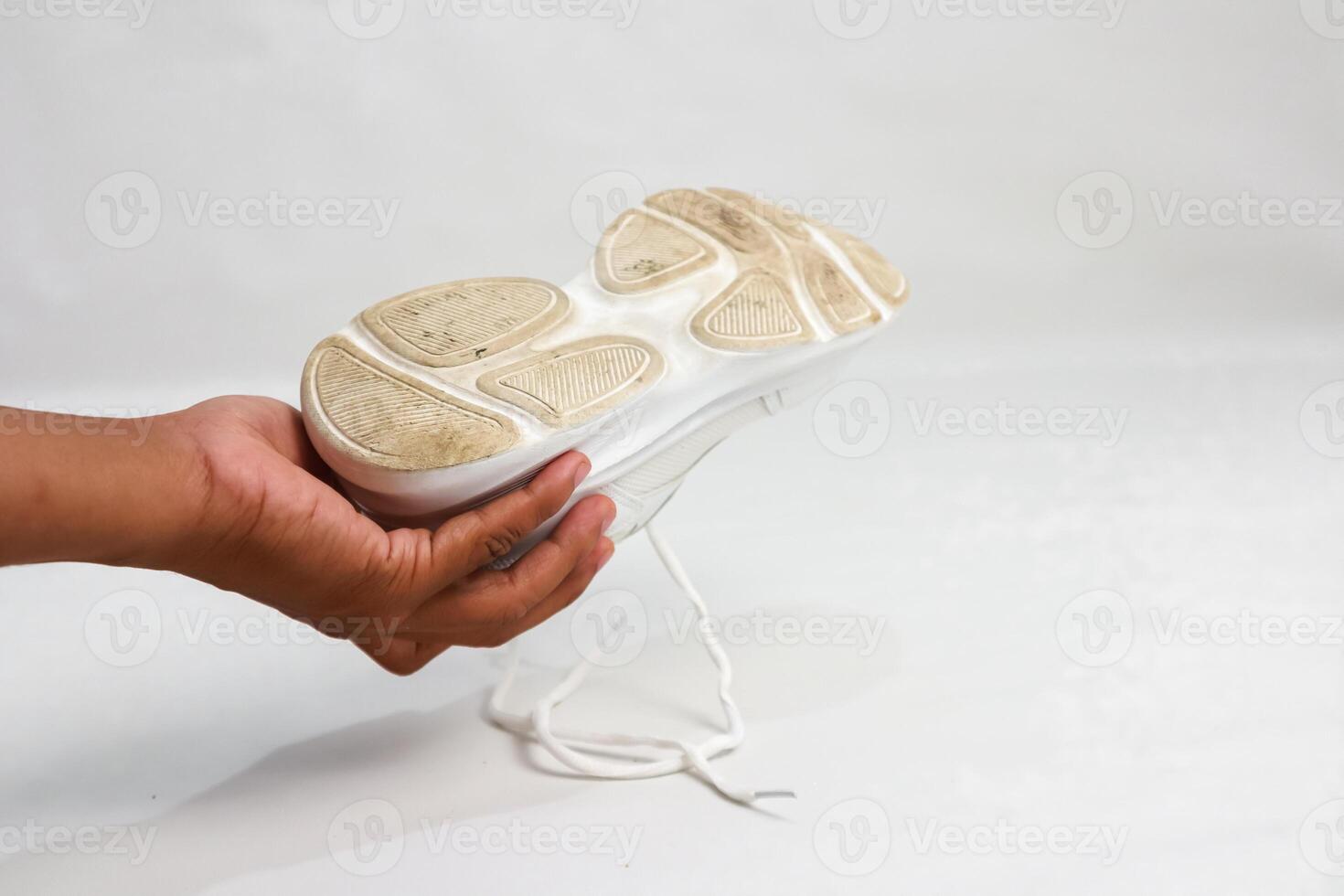 Examining the Sole of a White Athletic Shoe After Use, Highlighting Wear and Tear photo