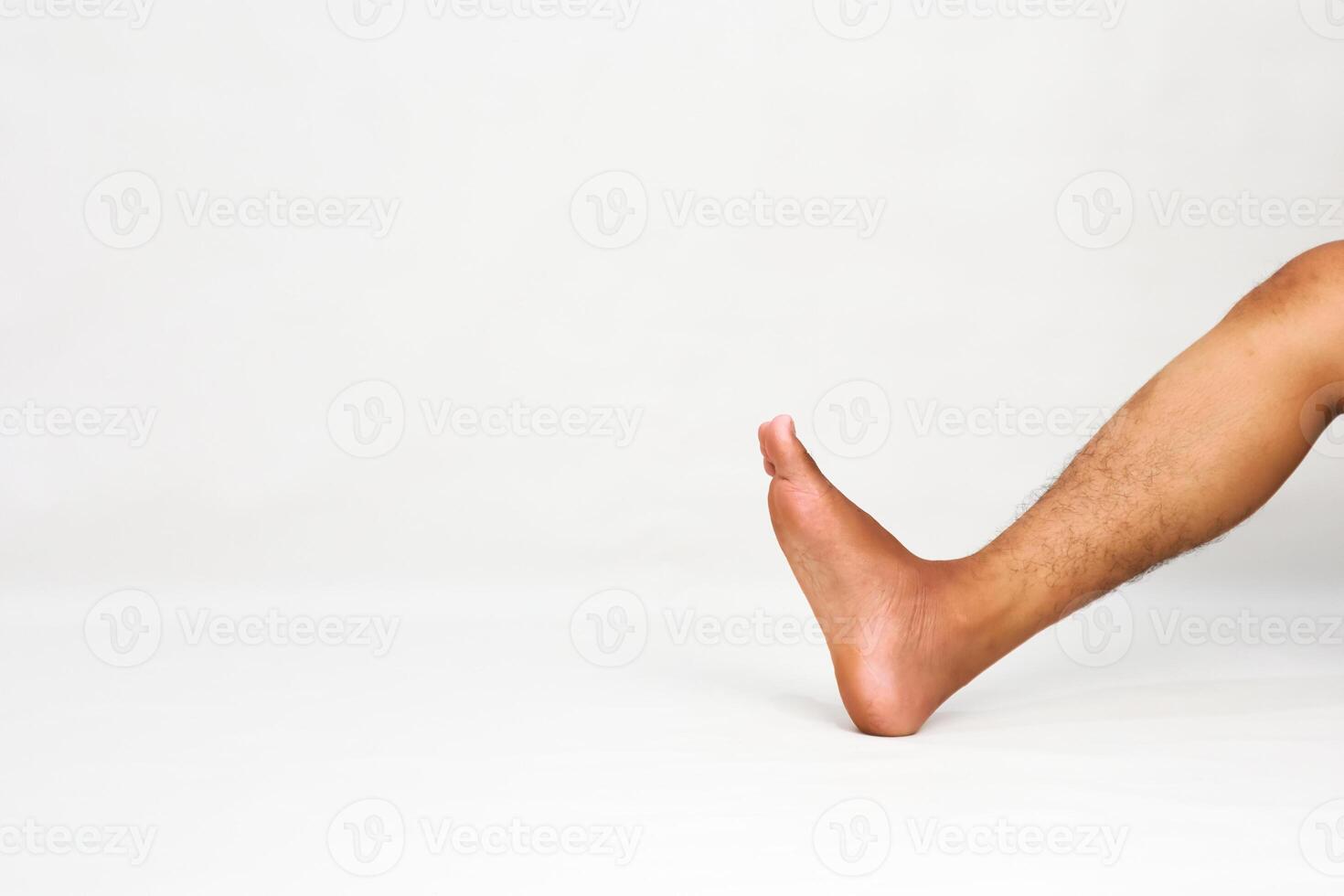 Close-up of a tanned male leg and foot angled against a white background promoting foot care photo
