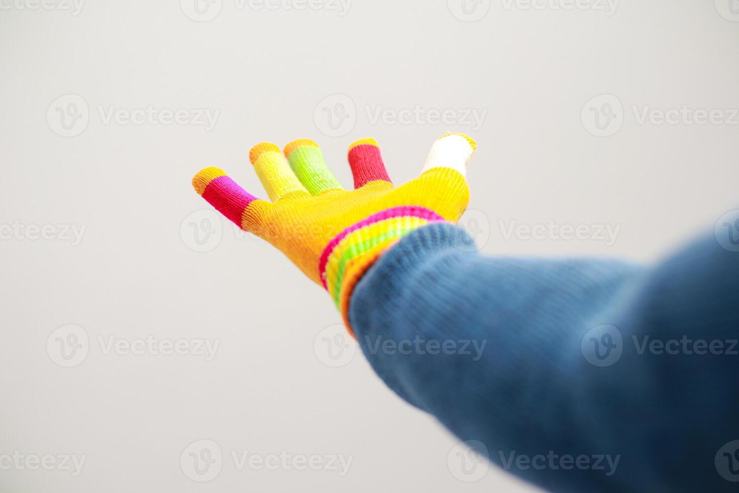 Brightly colored glove hand extended against a plain white backdrop conveys a sense of reaching photo