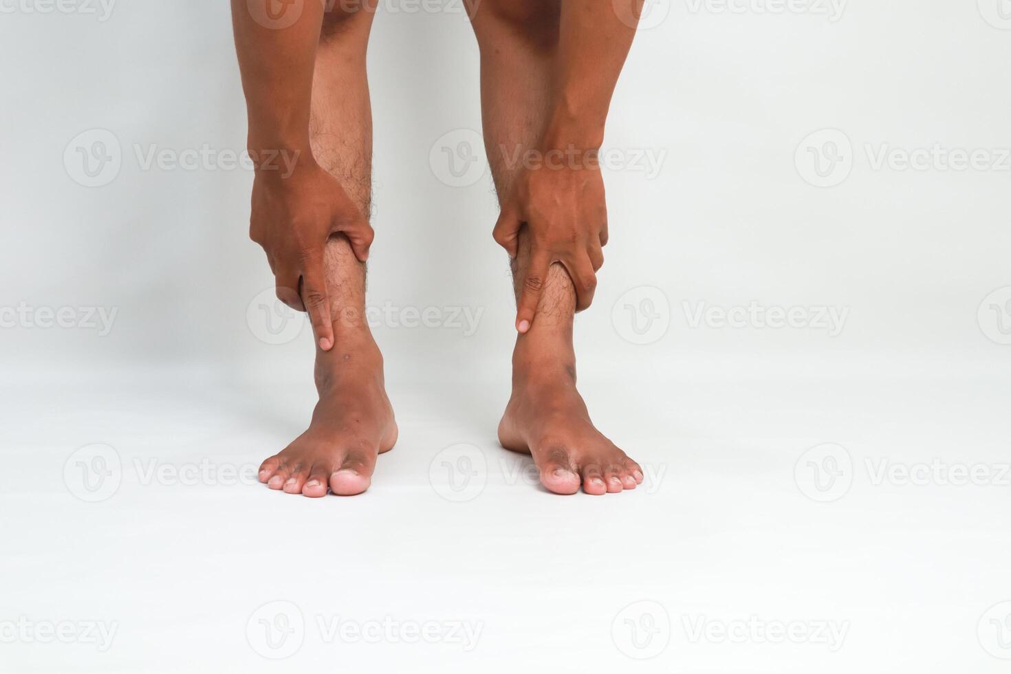 Person Experiencing Leg Pain or Discomfort, Holding Calves with Hands, on White Background photo