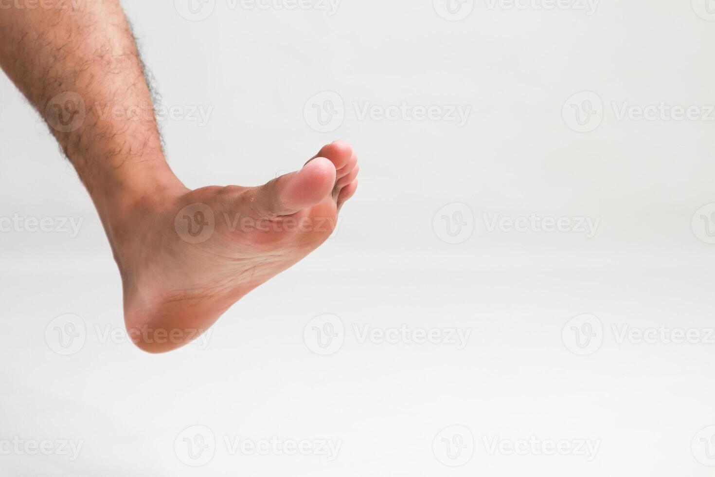 Isolated male foot on a white background showcasing toes, arch, and heel with leg photo
