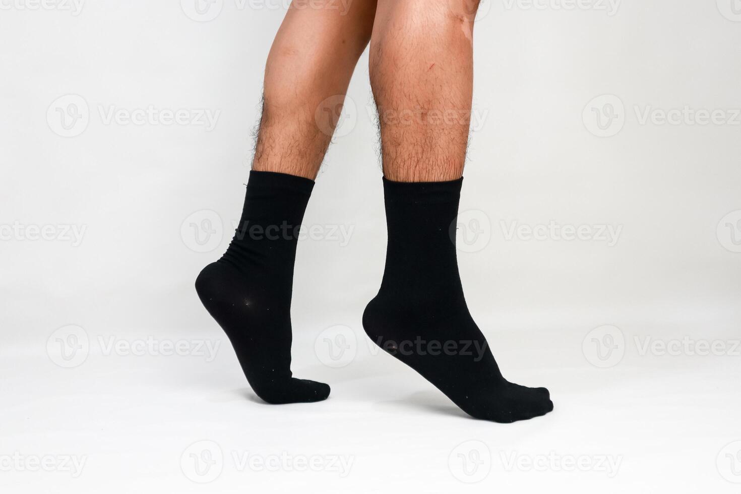 A close-up studio shot showcasing a man's legs and feet wearing black socks on white background photo