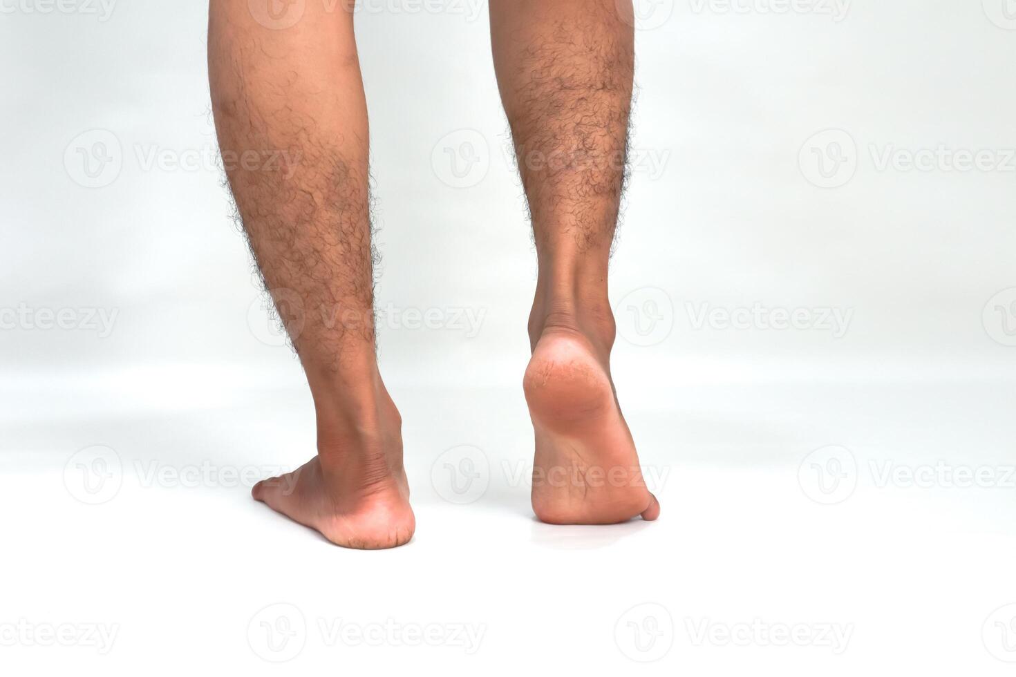 Close-up of a man's hairy legs and feet from the rear isolated against a white background emphasizing the lower extremities photo