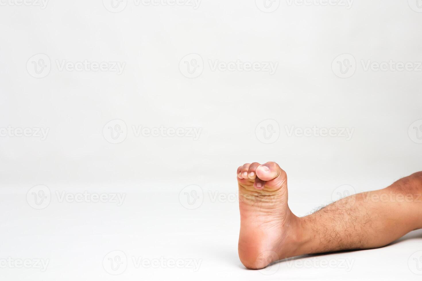 Close-up shot of a man's bare foot showing toes and skin texture in a clean studio setting on white backdrop with lots of negative space photo