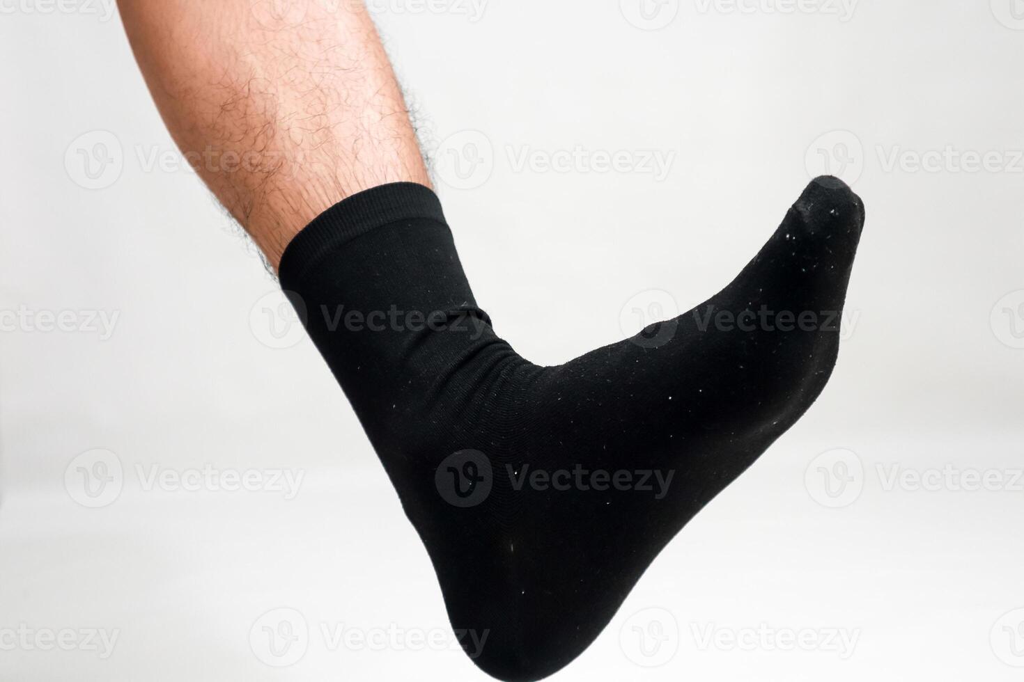 Isolated shot of a hairy leg and foot wearing a black sock on a white background, perfect for hosiery advertising photo