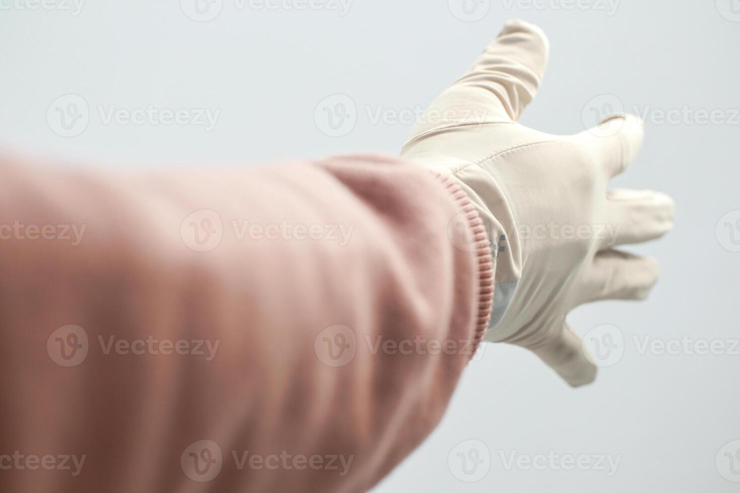 Gloved hand reaching out, fingers extended against a soft white backdrop, suggesting assistance photo