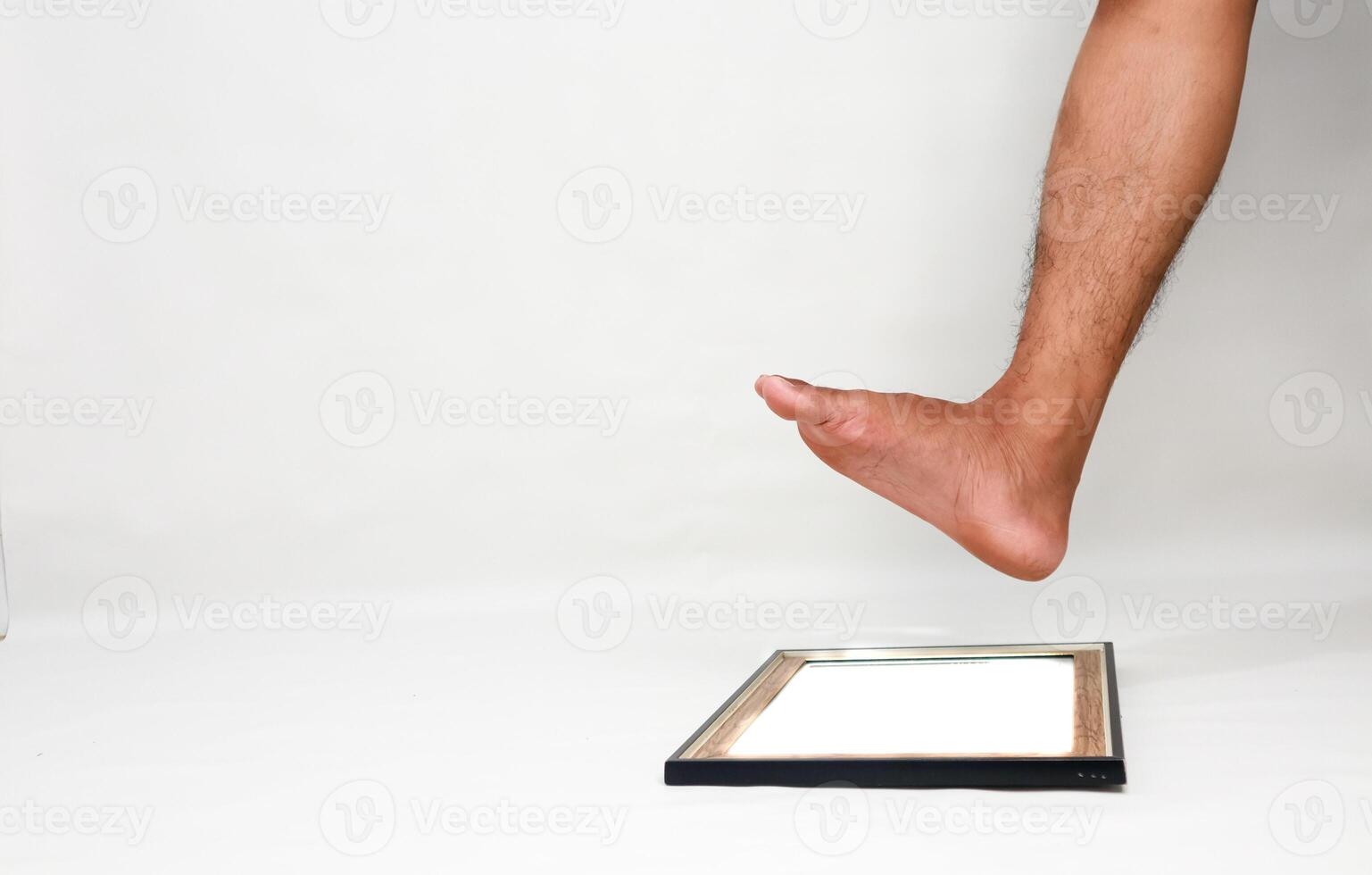Concept of stepping over boundaries or limits, represented by foot about to step on picture frame photo
