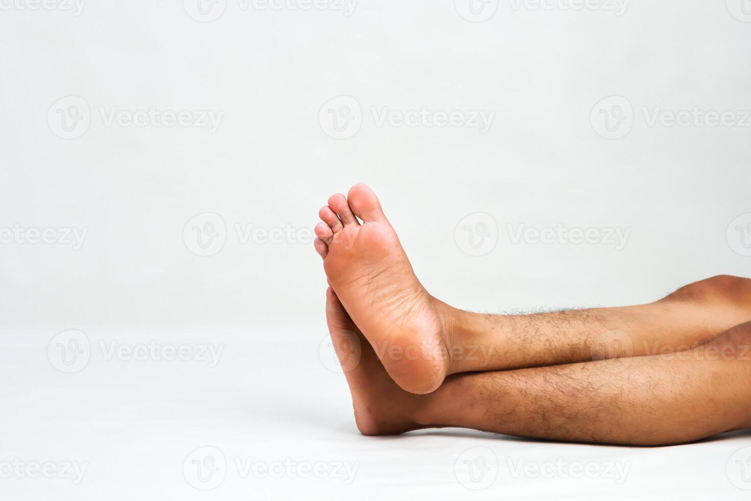 Close-up of a man's bare feet crossed against a white background in a studio setting providing ample copy space for creative use photo